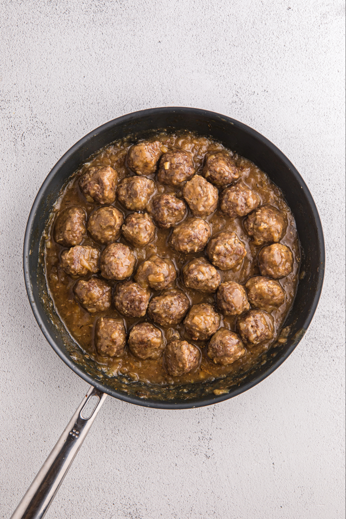 Cooked meatballs in a skillet with gravy.