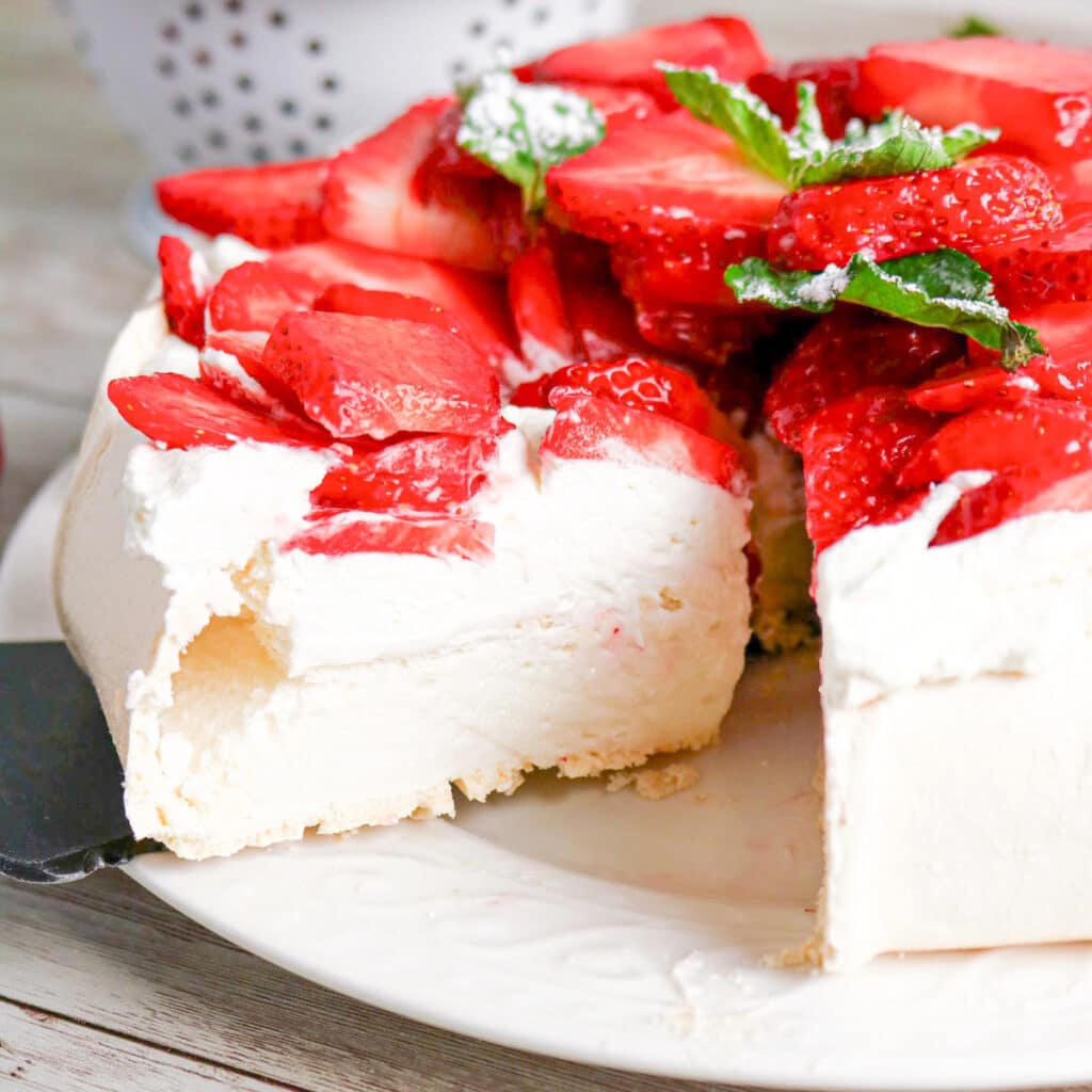A slice of strawberry pavlova under a serbing spatula.