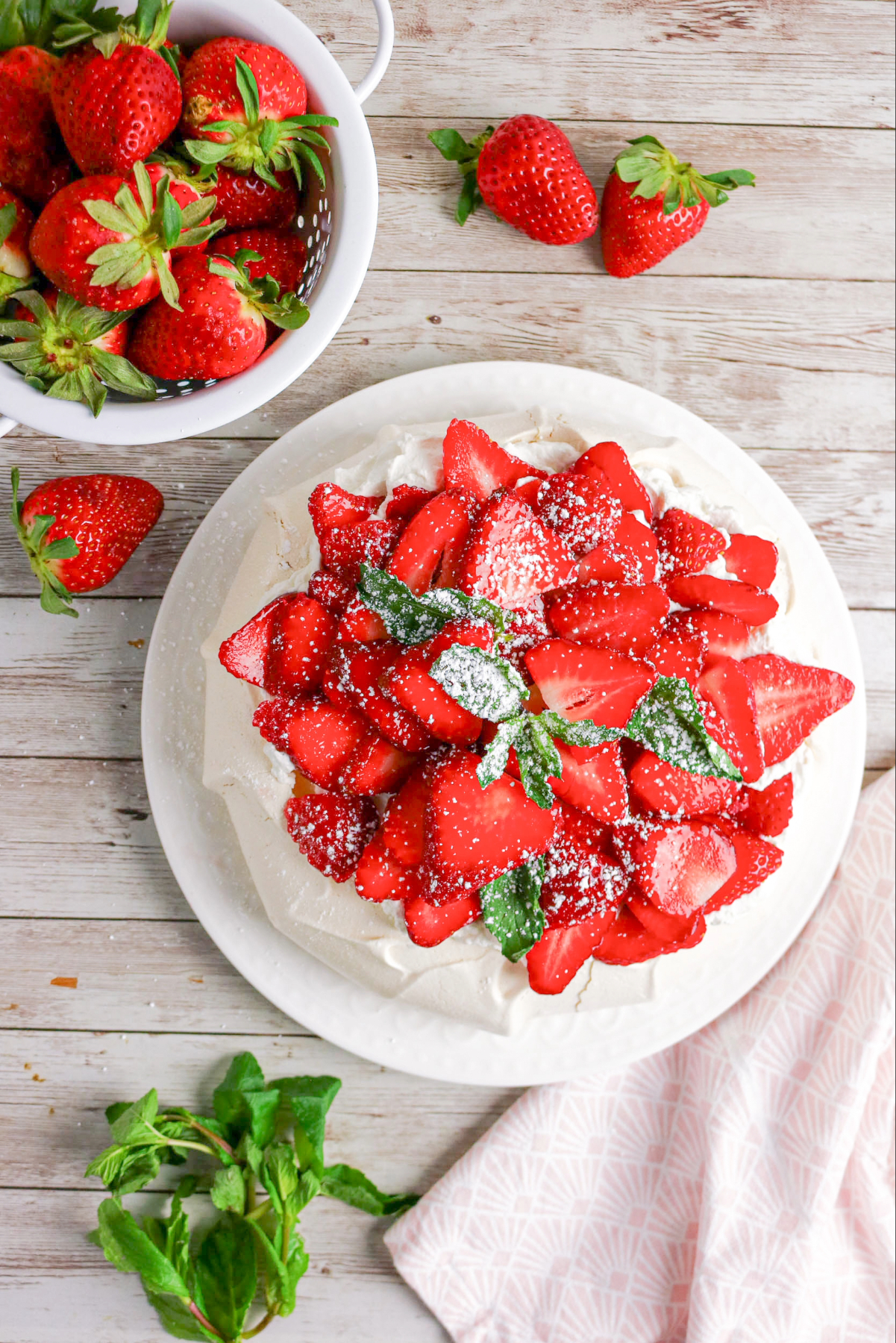 Overhead view of strawberry pavlova with a basket of fresh berries on the side.