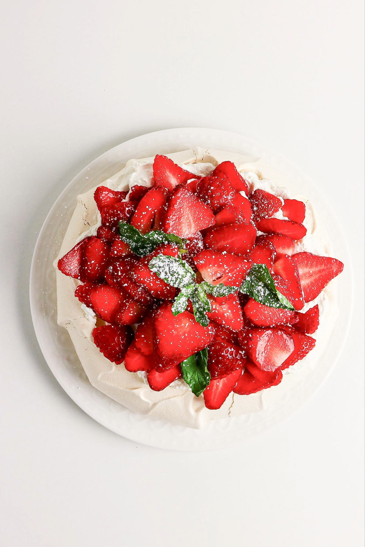 pavlova shell with whipped cream topped with sliced strawberries.