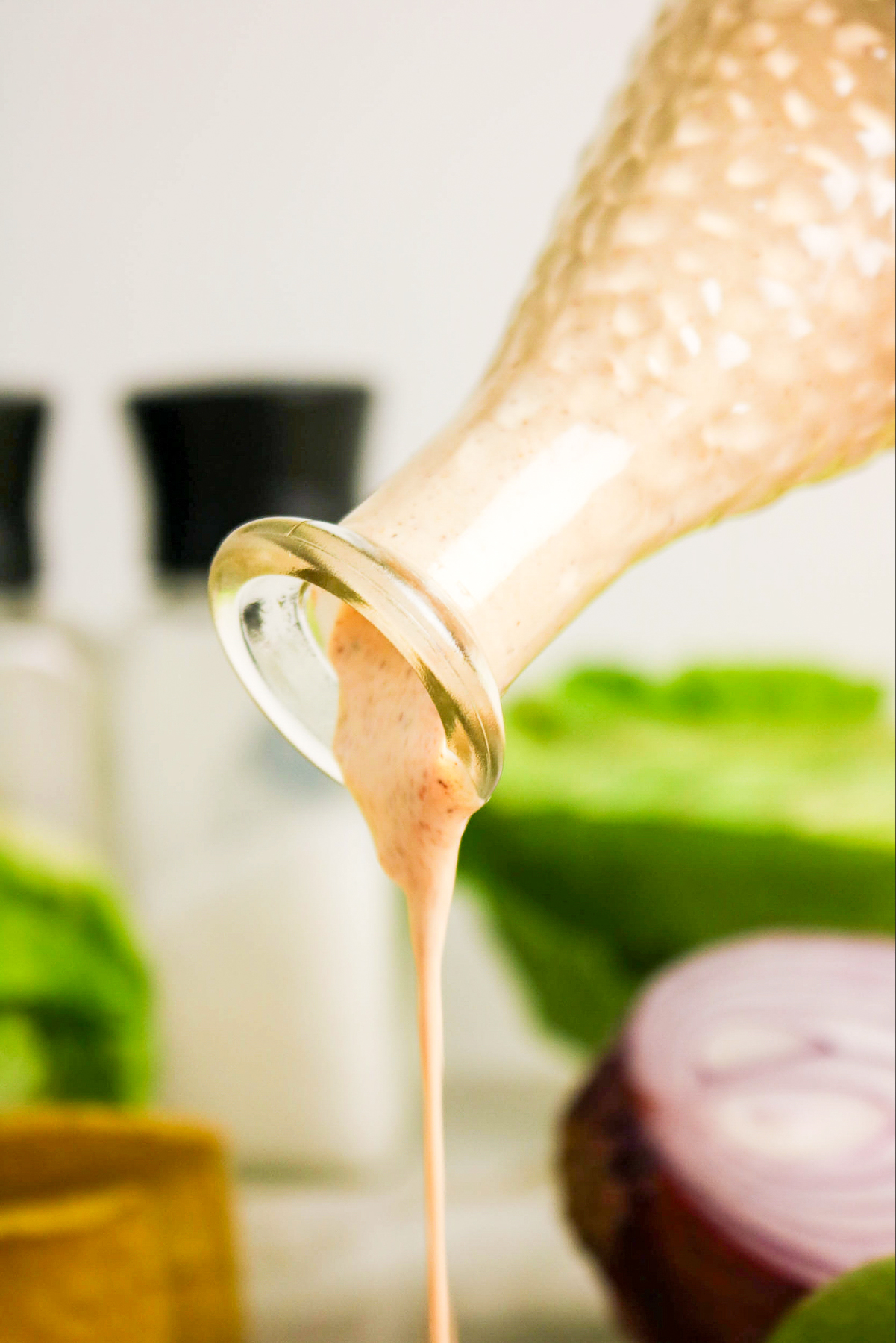 Pouring salad dressing over salad.