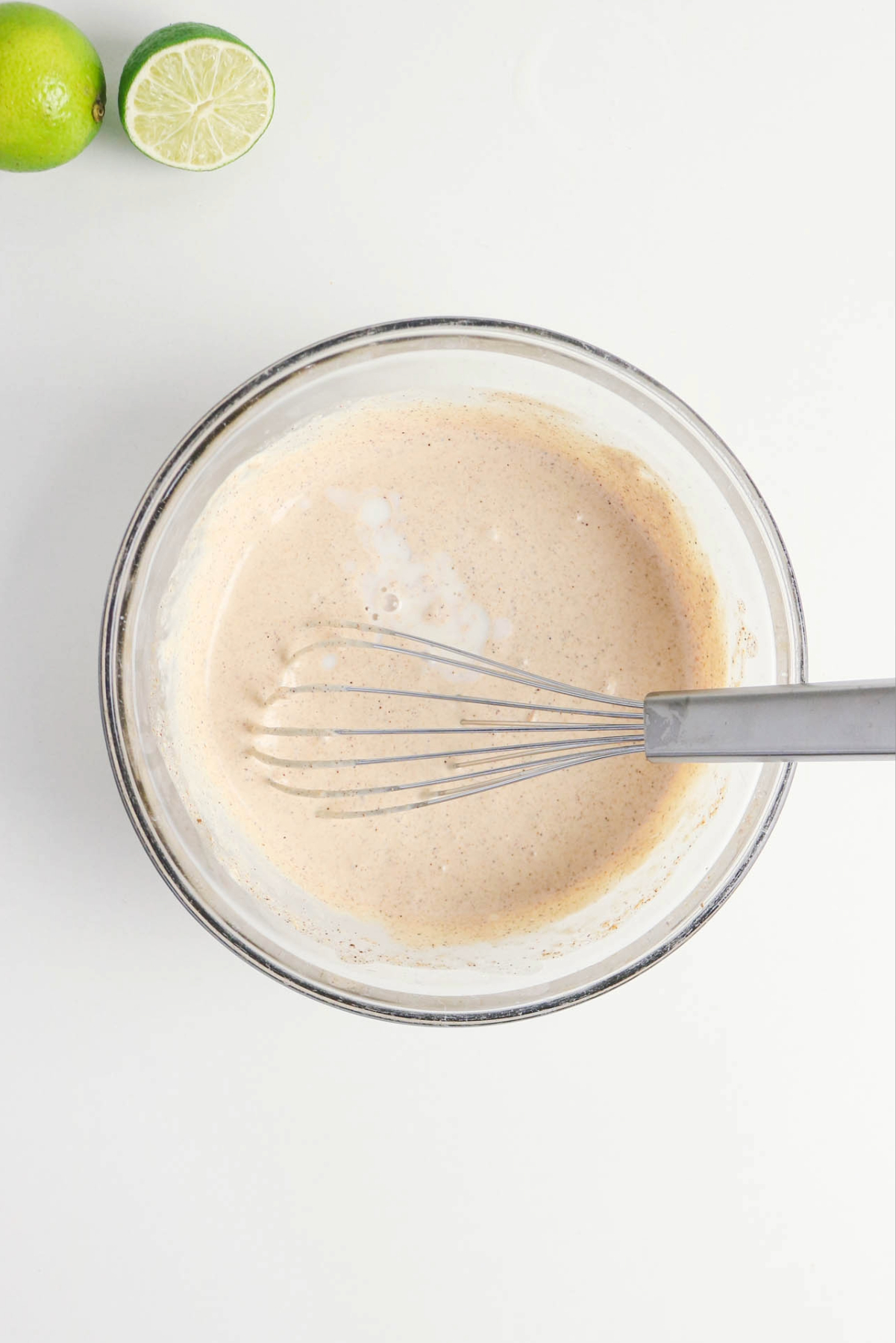 Taco salad dressing recipe mixed in a clear bowl with a whisk.