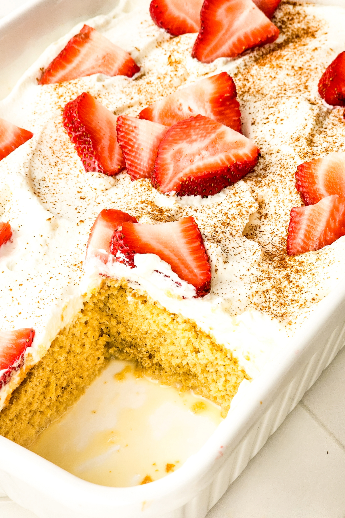 Top view of tres leches cake with whipped cream and strawberries.