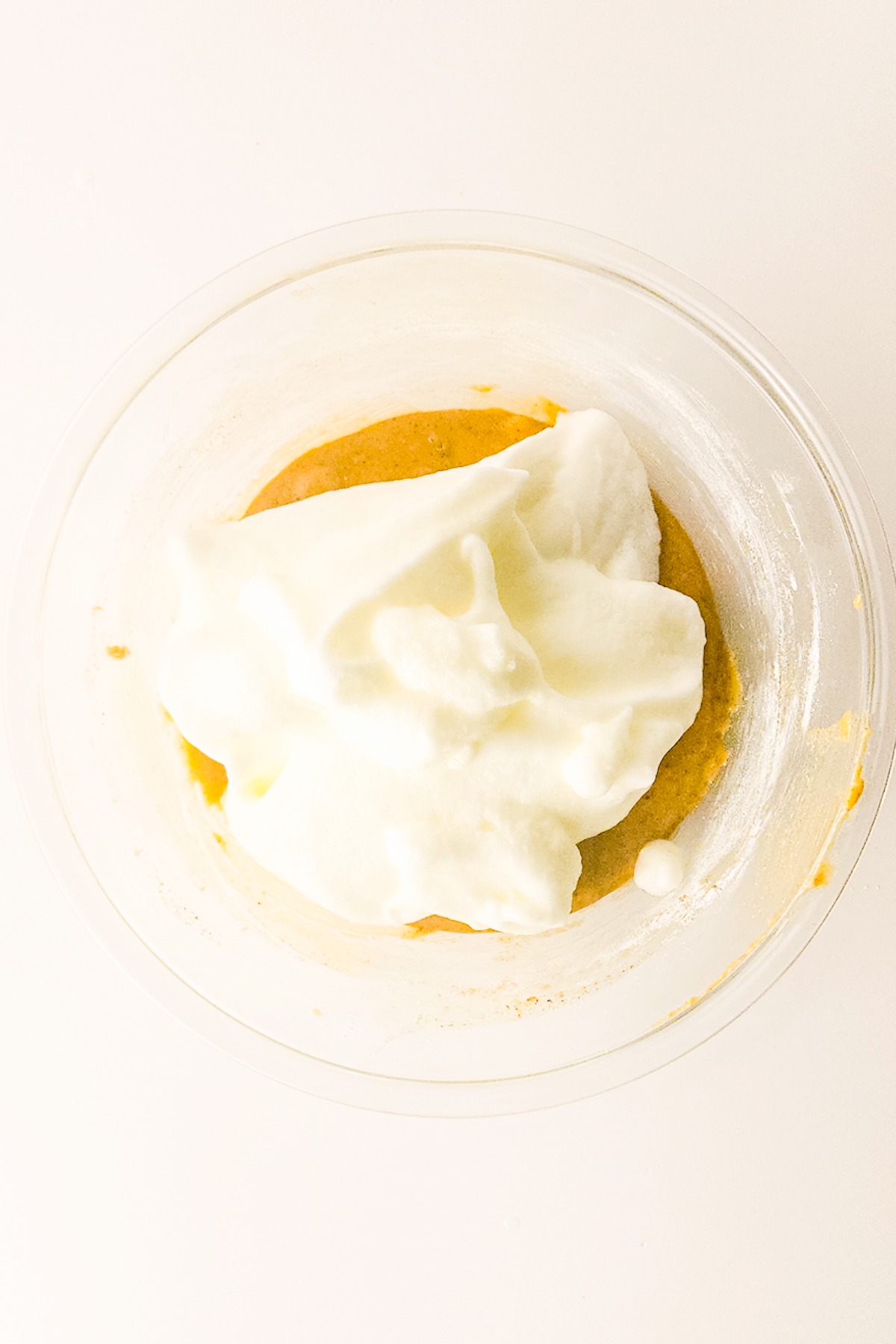 Fluffy egg whites with cake batter in a mixing bowl before combining.