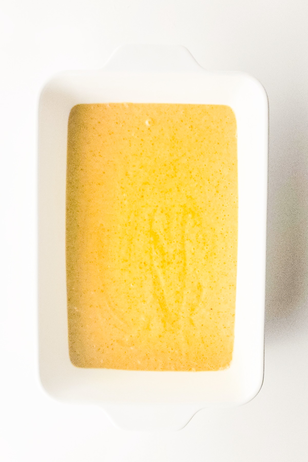 Cake batter in a greased baking dish before baking.