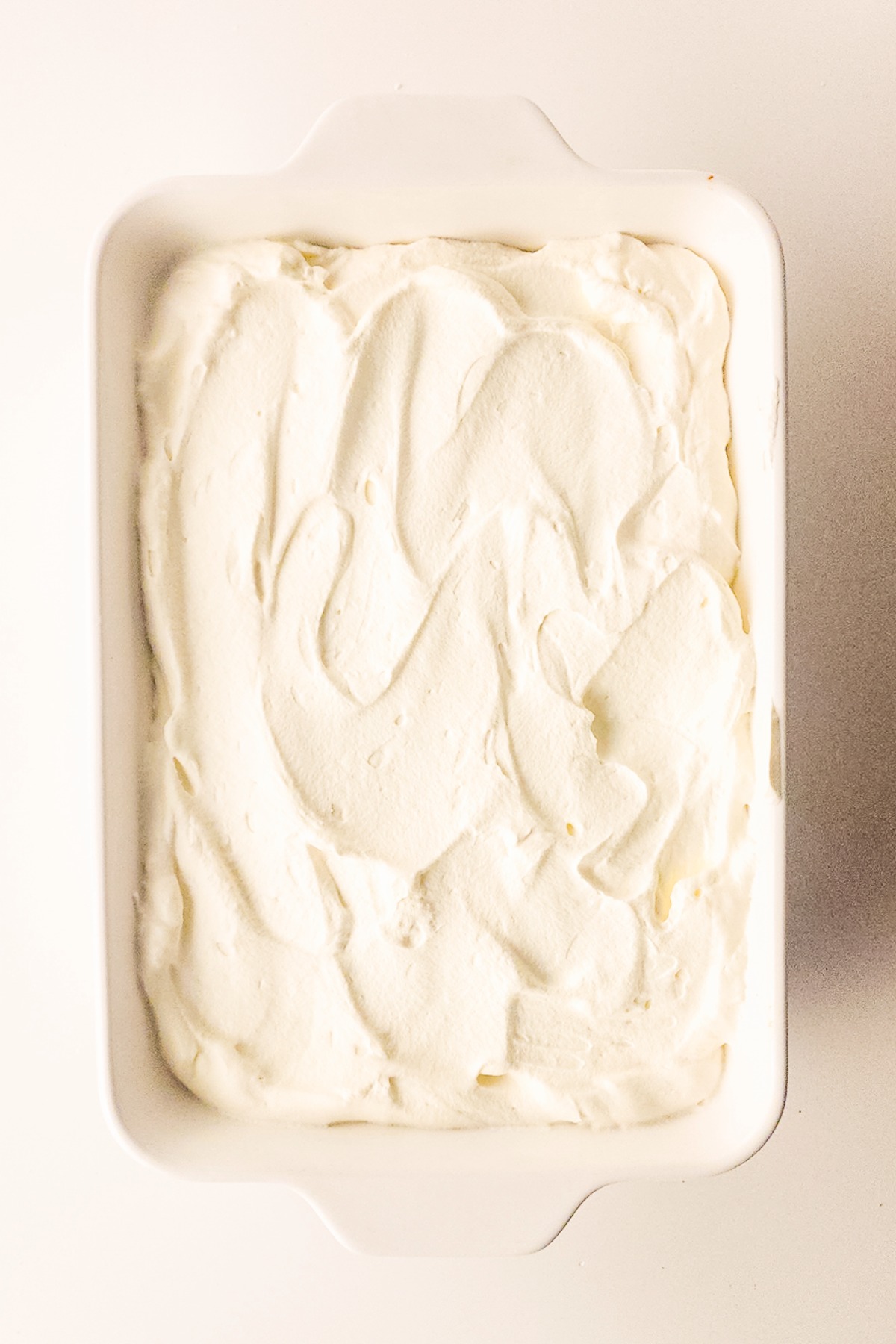 Whipped cream over tres leches cake before garnishing.