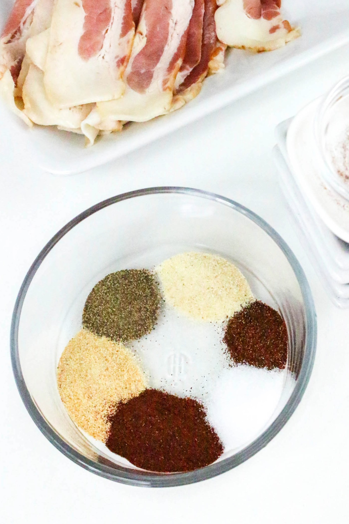 Seasoning spices in a clear bowl before mixing together.