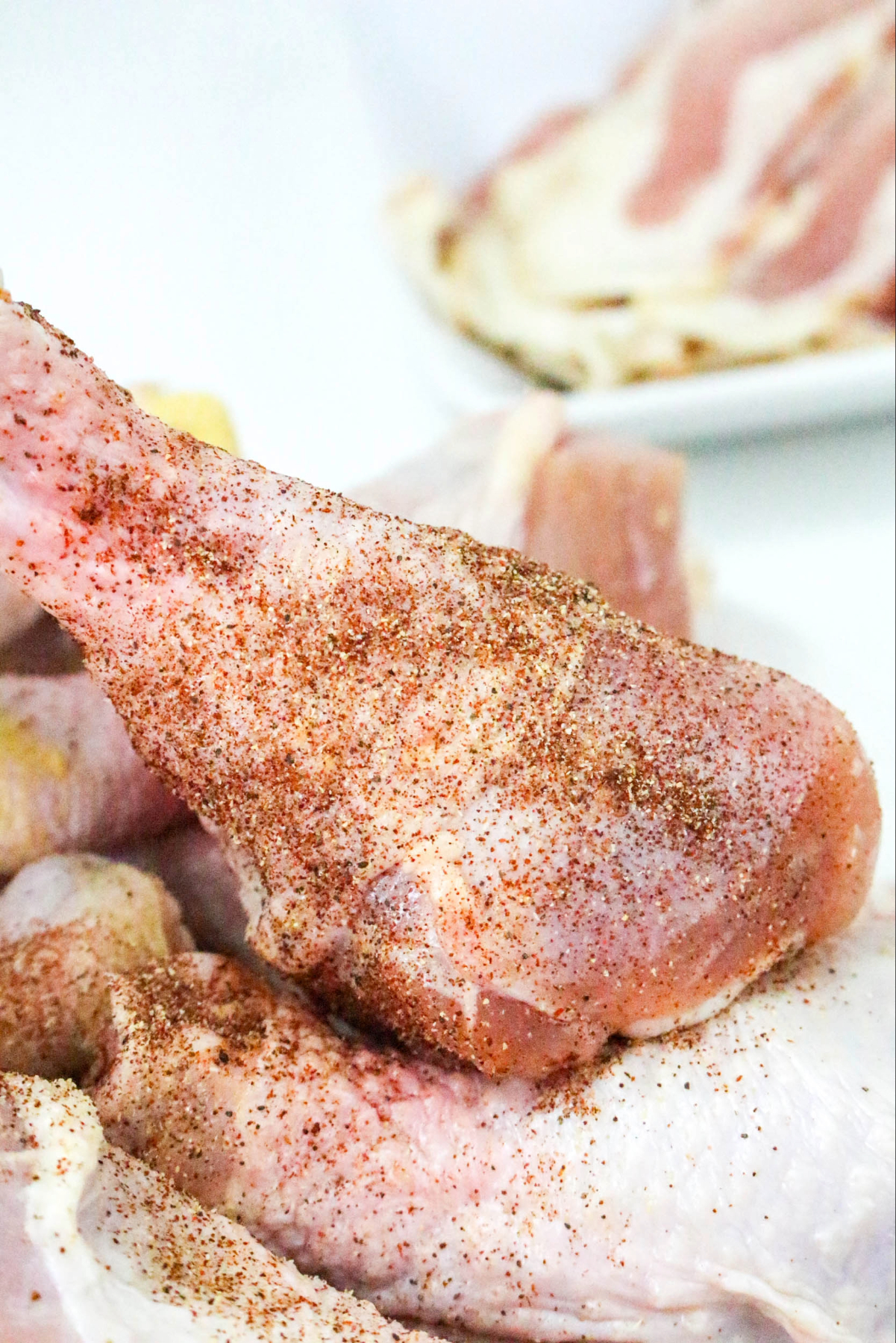 Chicken drumsticks with seasoning before cooking.