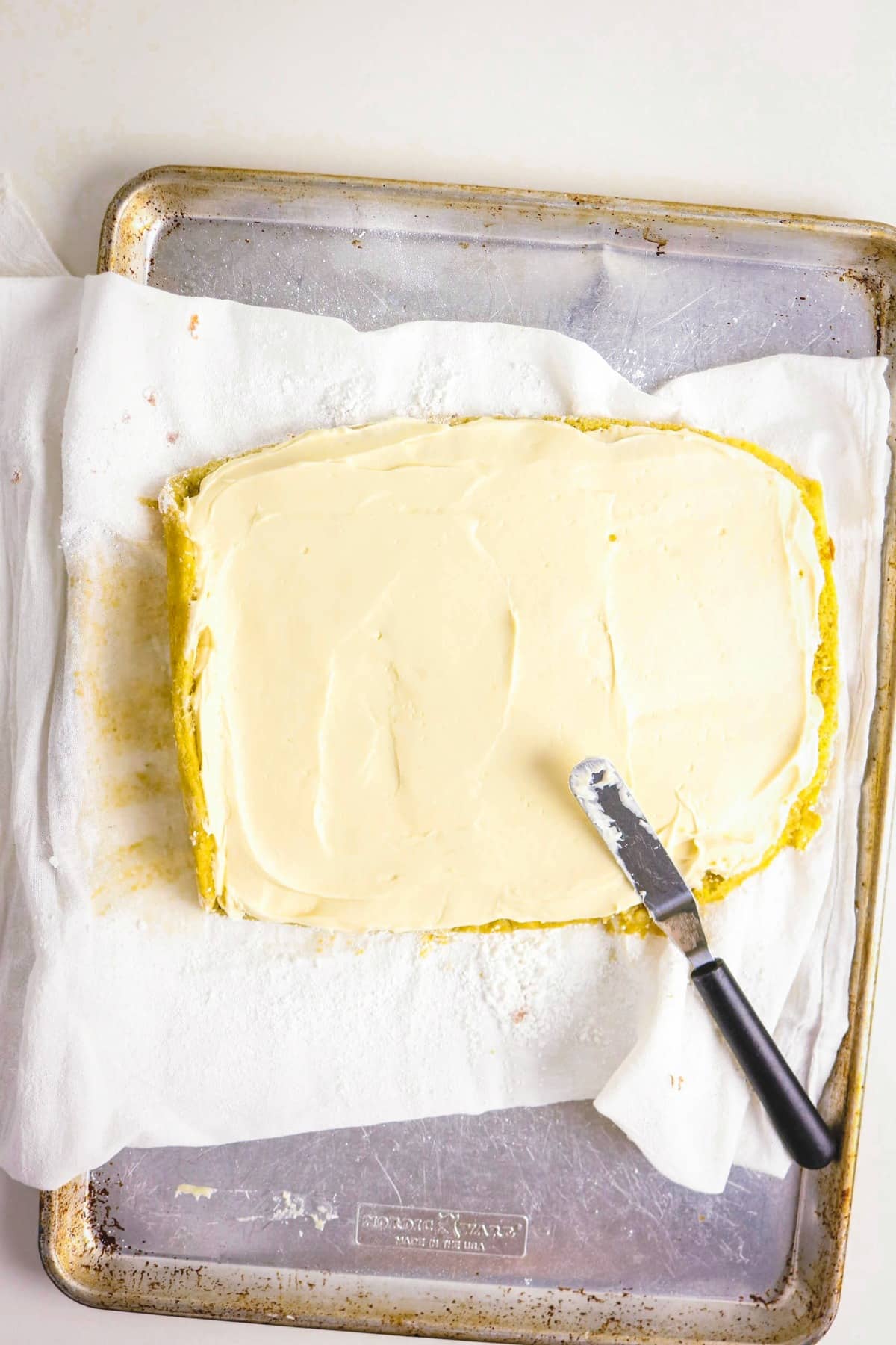 topping cream cheese on a banana cake before rolling.