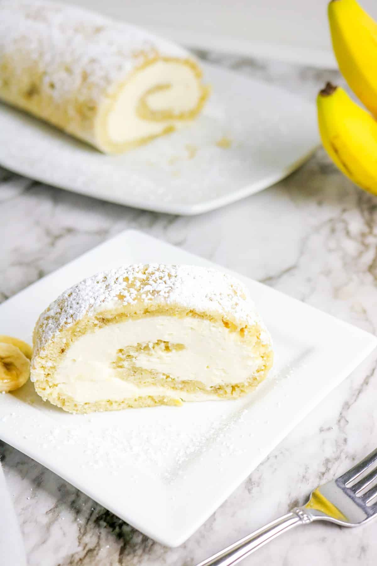 A slice of cake on a plate with the entire cake in the background.