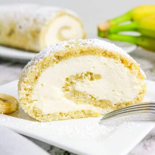 A slice of banana roll cake with cream cheese filling on a white plate.