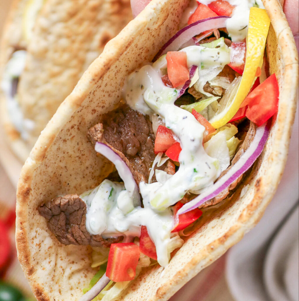 Beef gyros with tzatziki sauce in a pita bread.