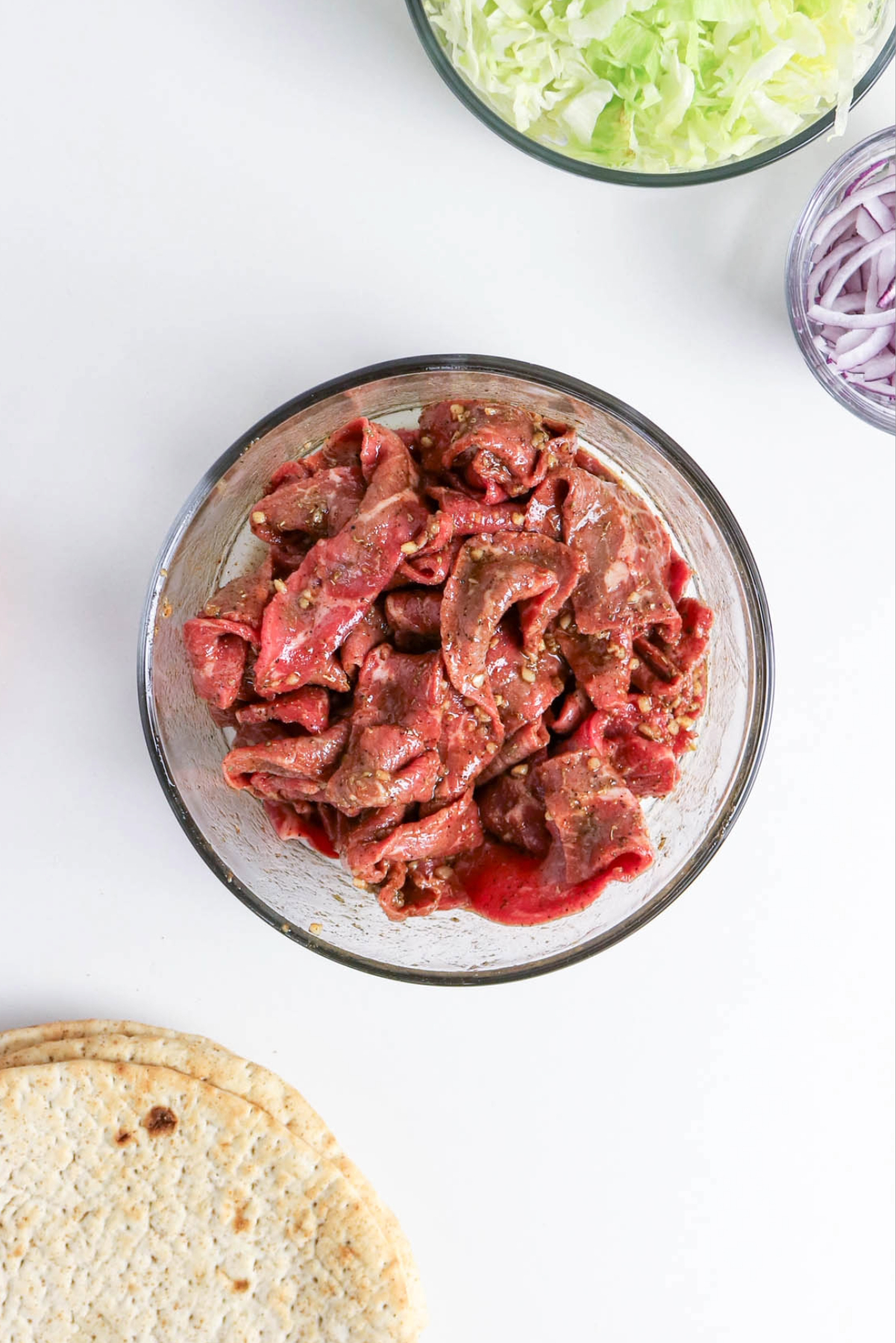 Marinated beef in a clear mixing bowl.