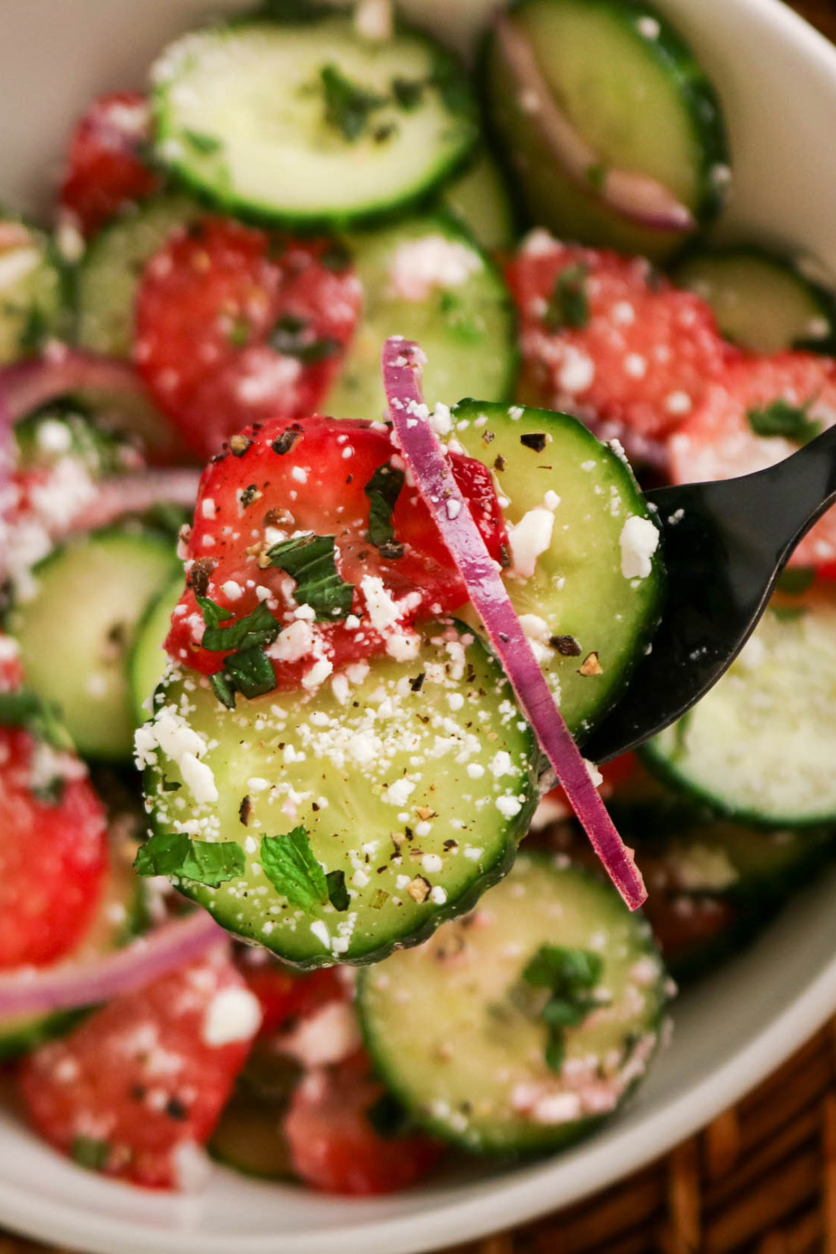 Close shot of salad with cucumbers on a fork.