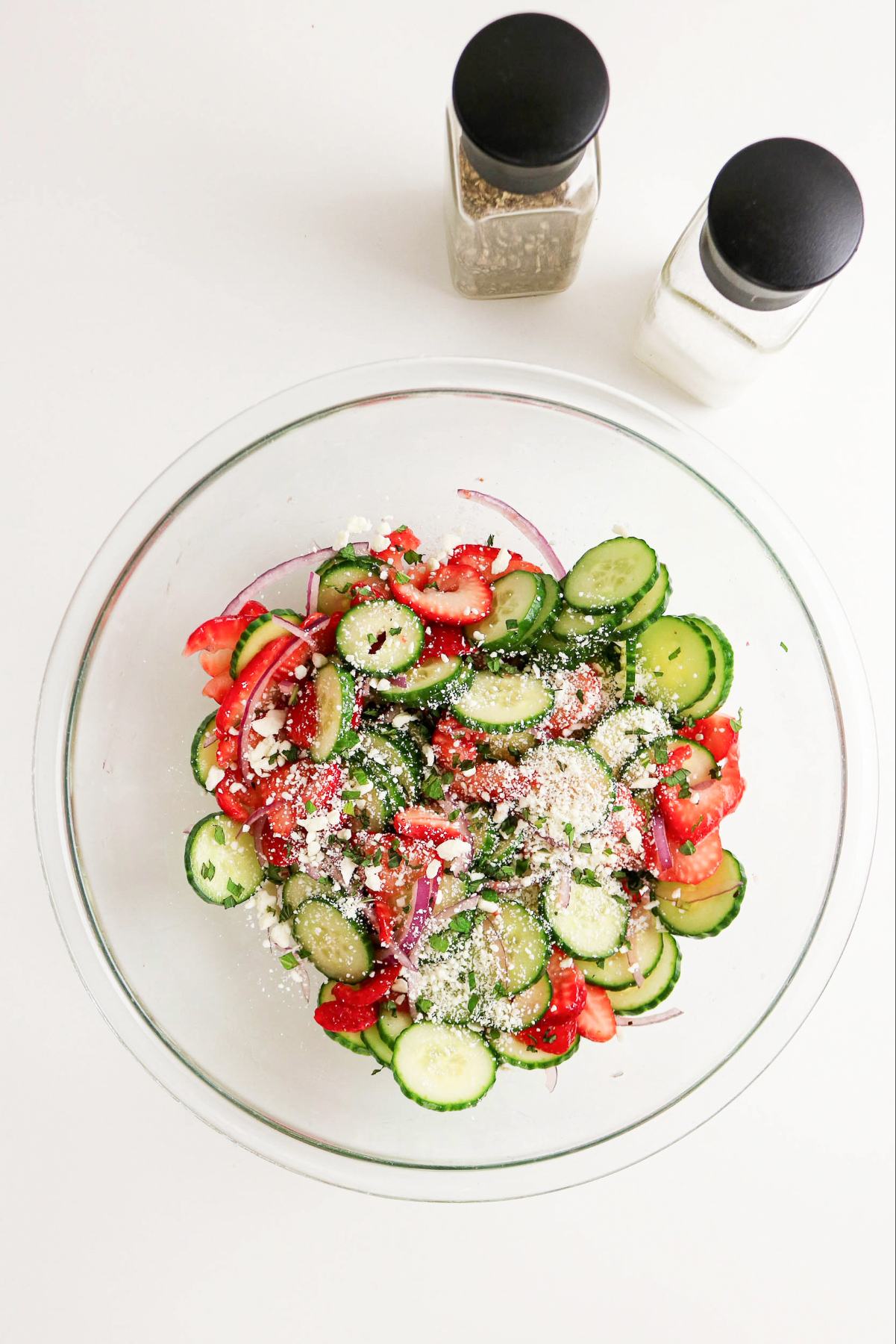 Sliced cucumber and strawberries topped with feta cheese and sliced onions.