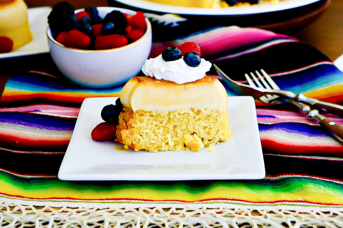 Vanilla flan cake topped with whipped cream and fresh berries.