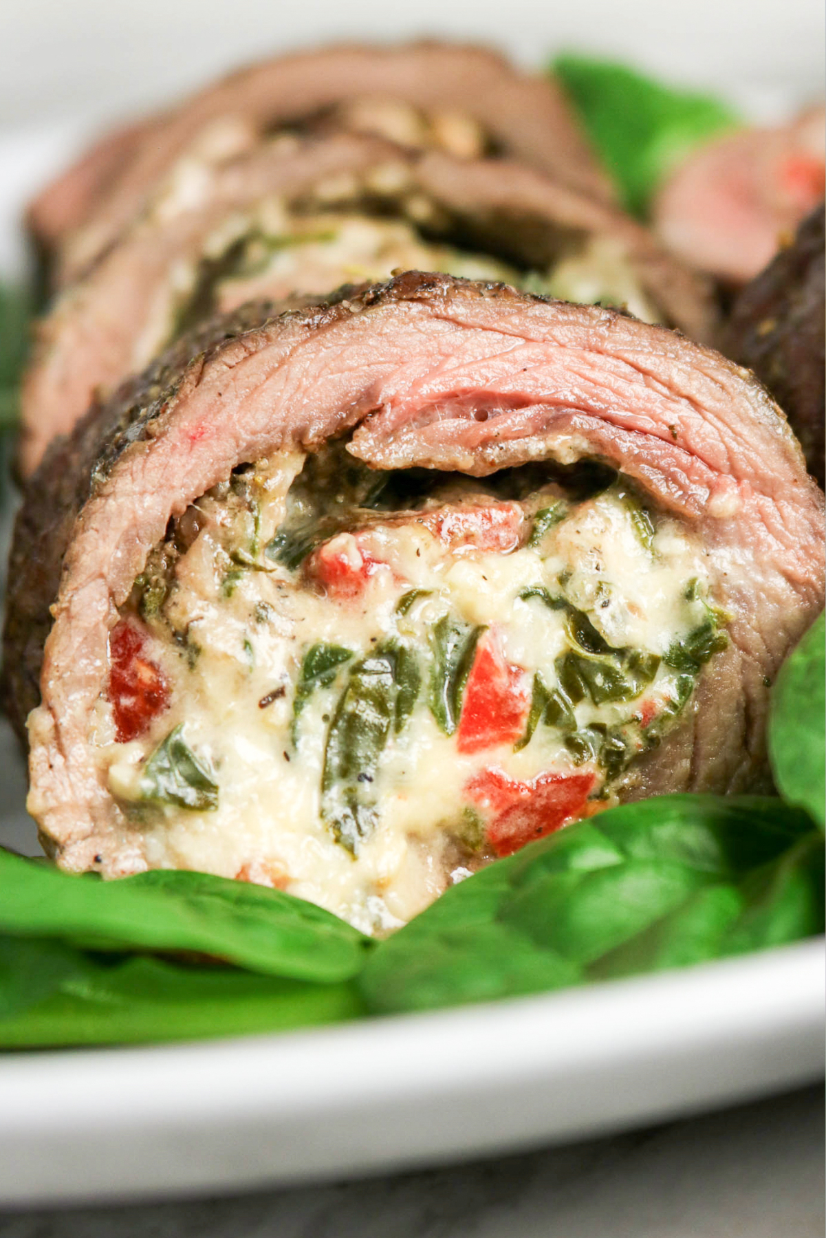 Beef flank stuffed wit cheese on a dinner plate.