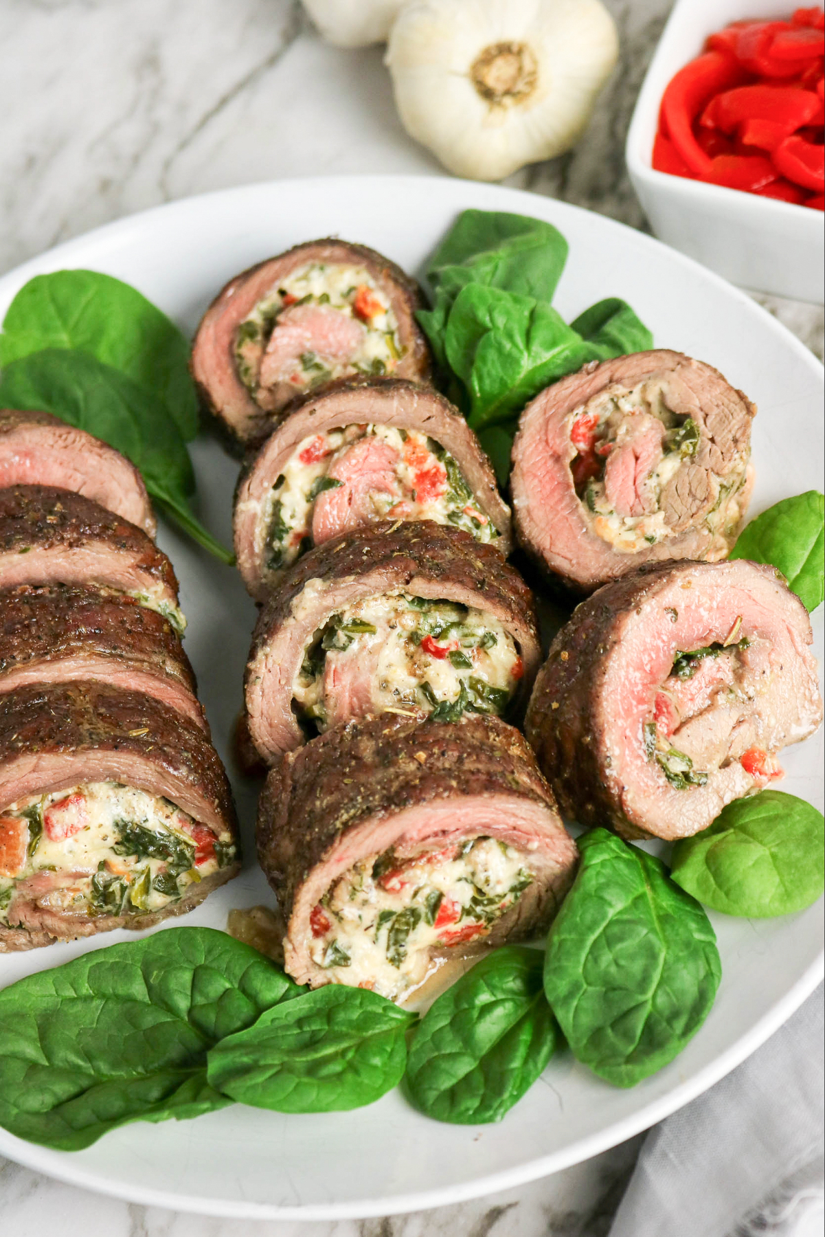 Overhead view of a platter with sliced stuffed flank steak.