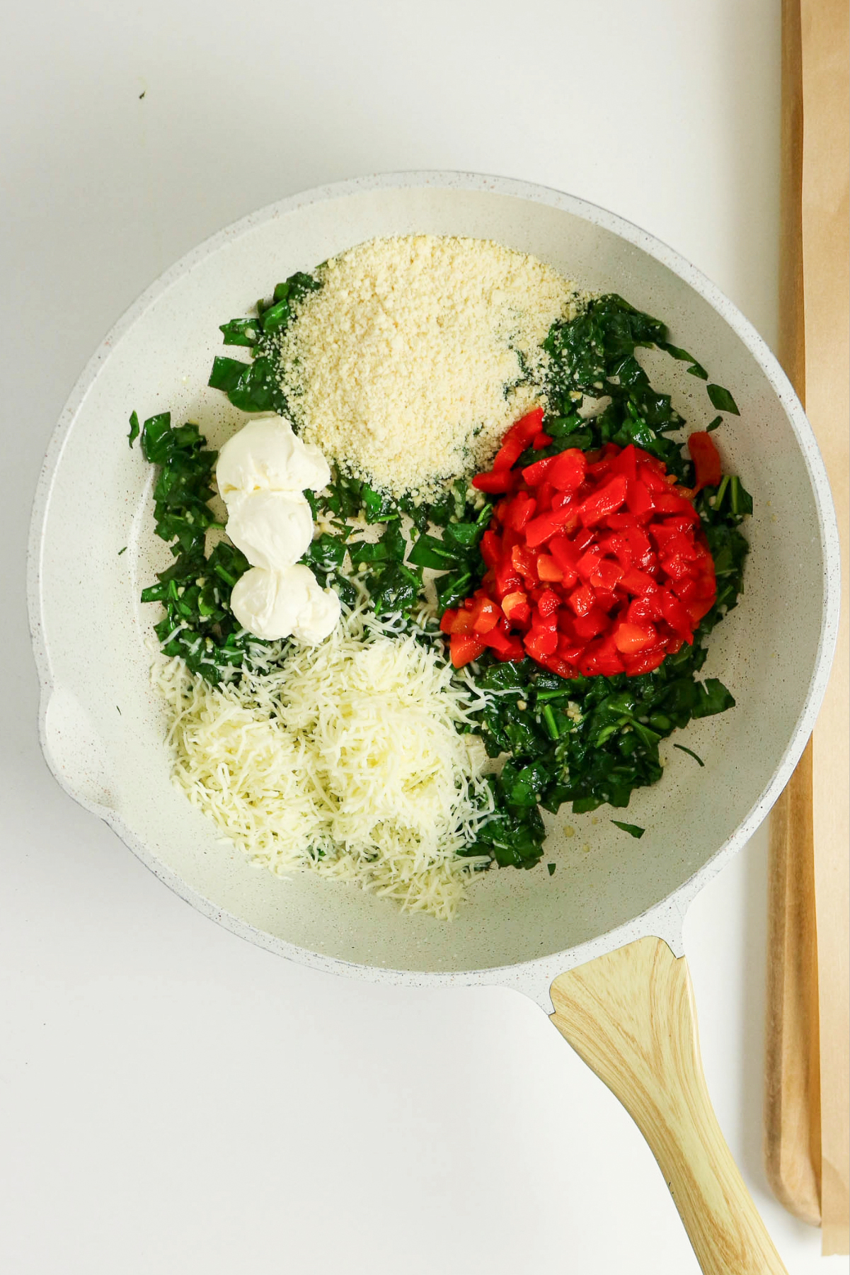 Cheese, spices and spinach in a sauce pan.