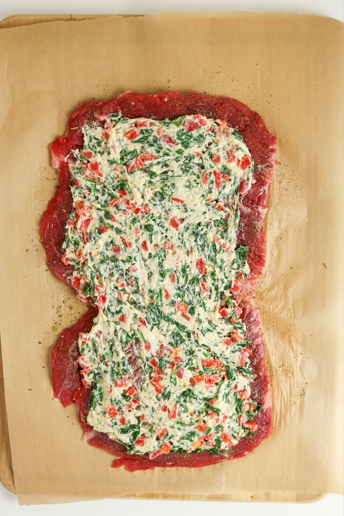 Filling spread on steak before rolling.