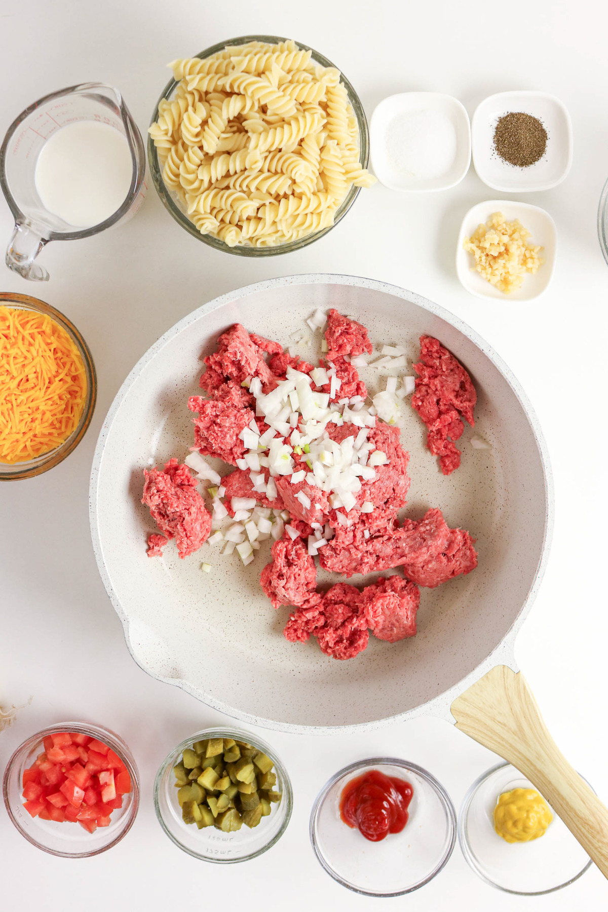 Ground beef in a skillet and onion before cooking.