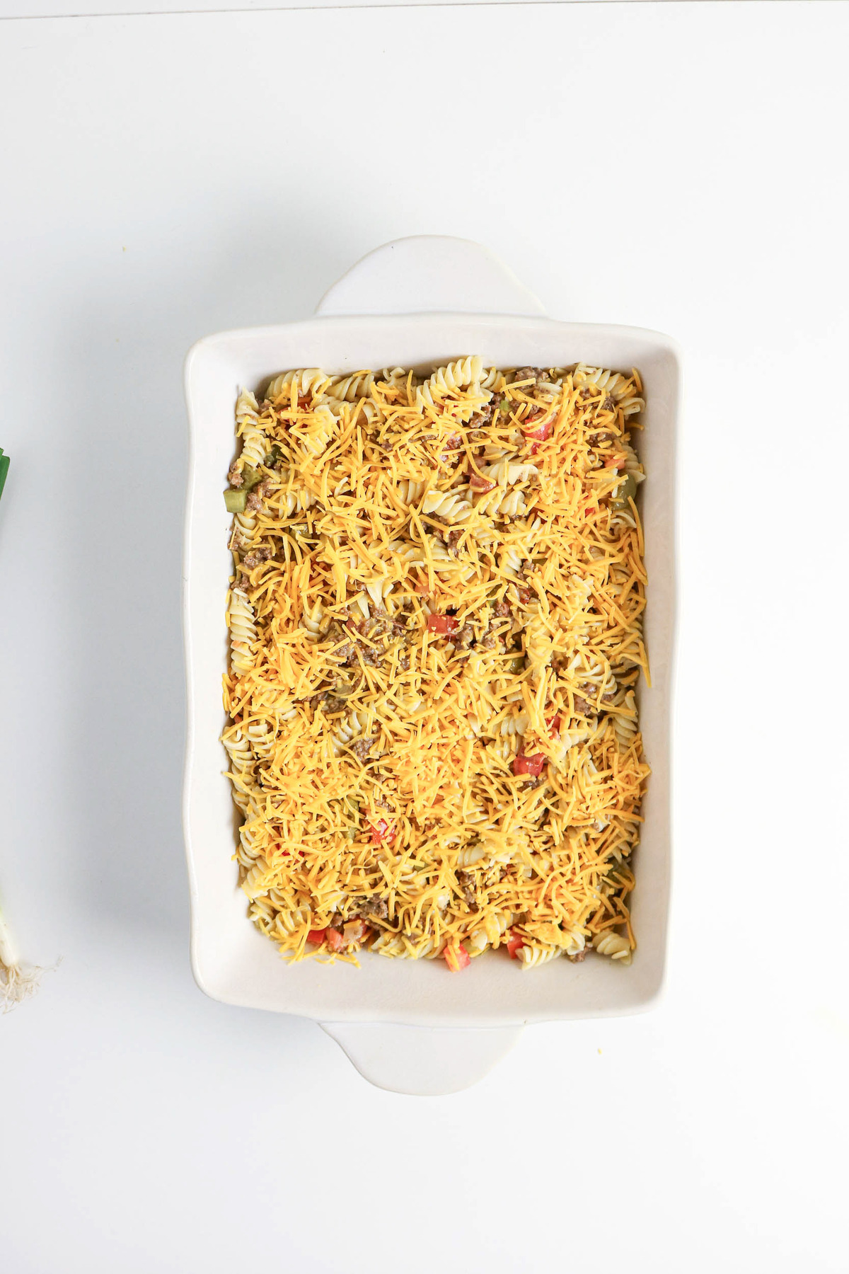 Cheese topped over casserole dish before baking.