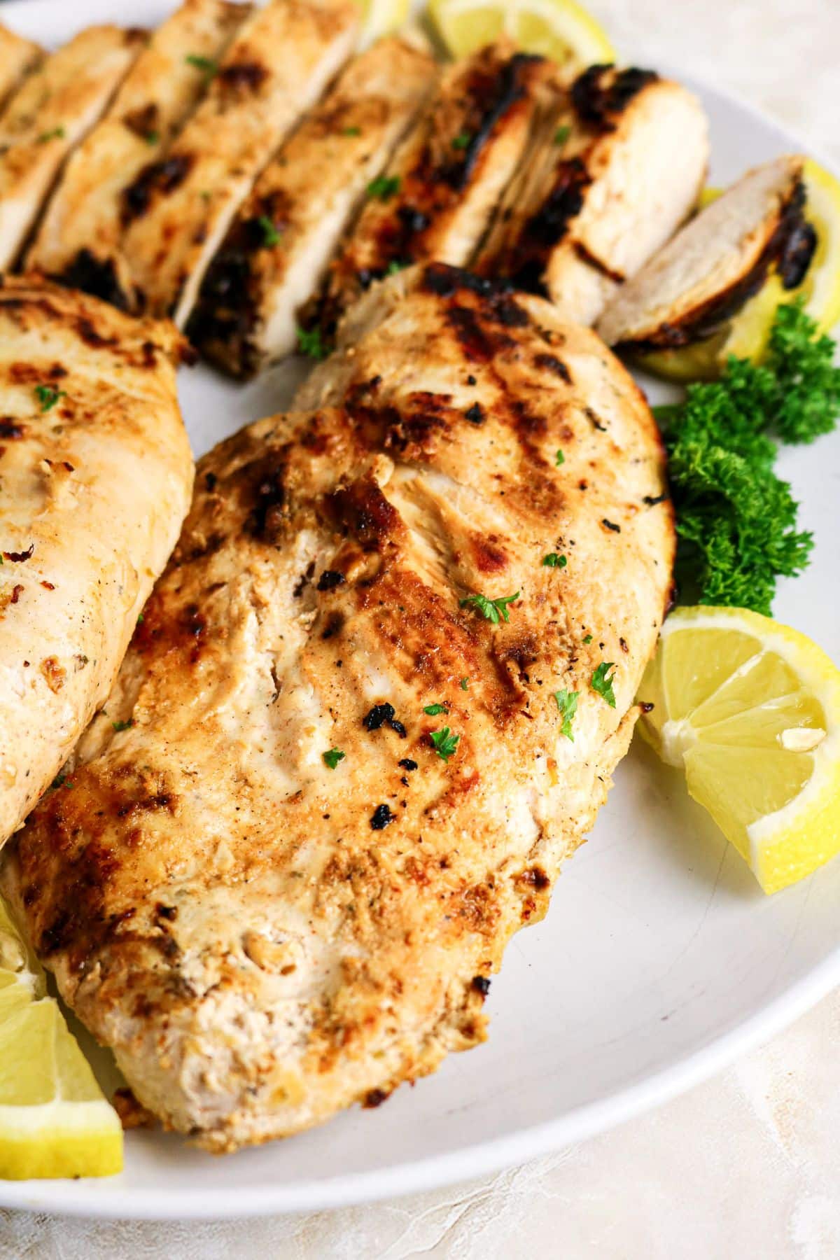 Grilled boneless chicken on a white platter.