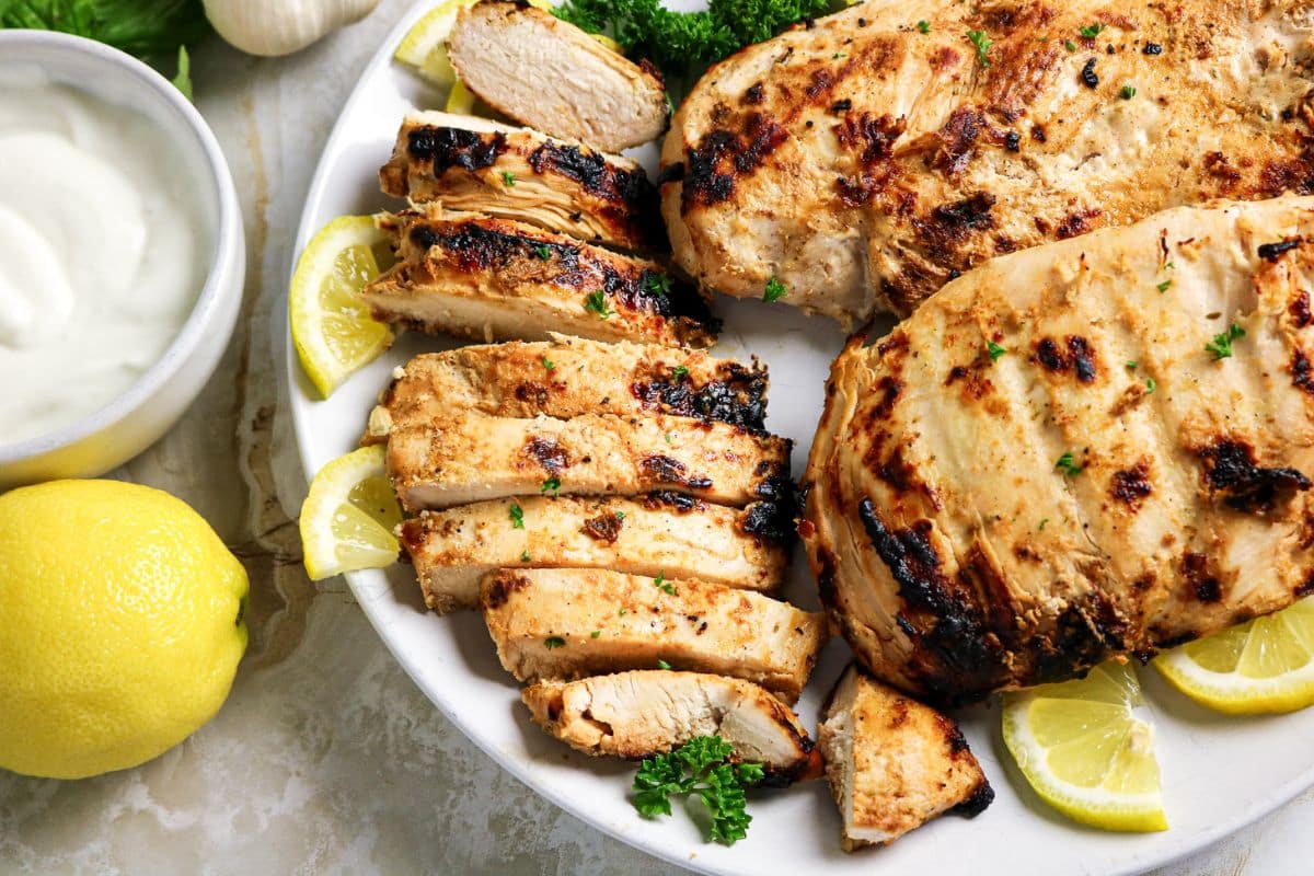 A platter of sliced chicken breasts with lemon.