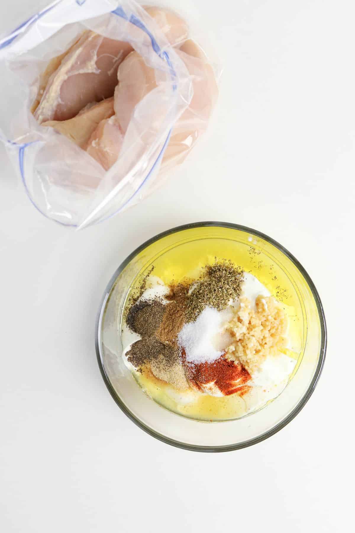 Greek yogurt marinate in a clear mixing bowl.