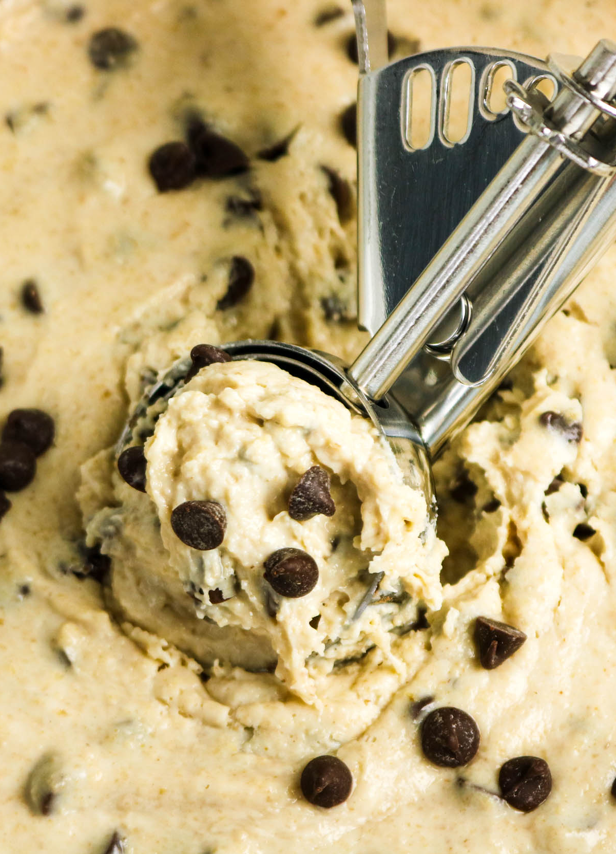 A close view of cottage cheese cookie dough with an ice cream scoop in the middle of the dough.