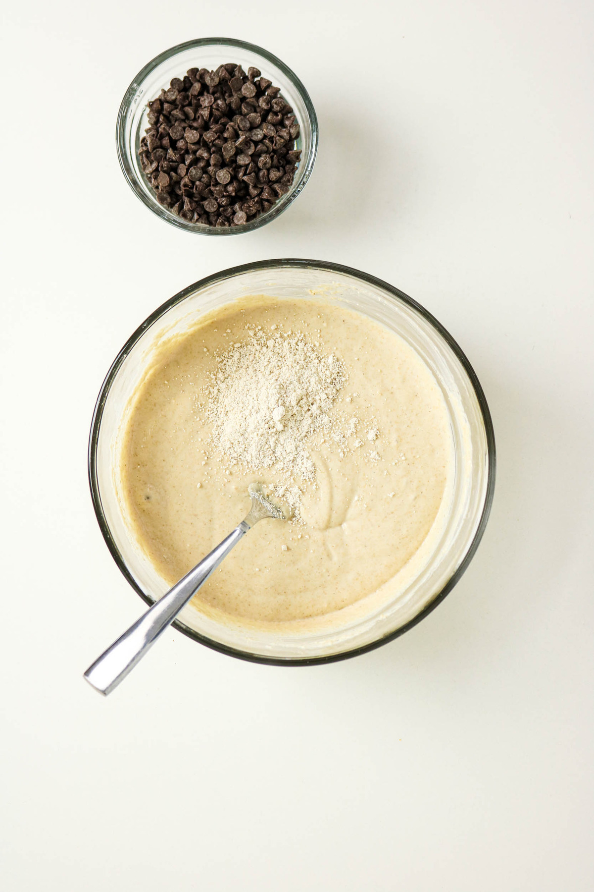 Oat flour added to mixed cottage cheese in a mixing bowl.