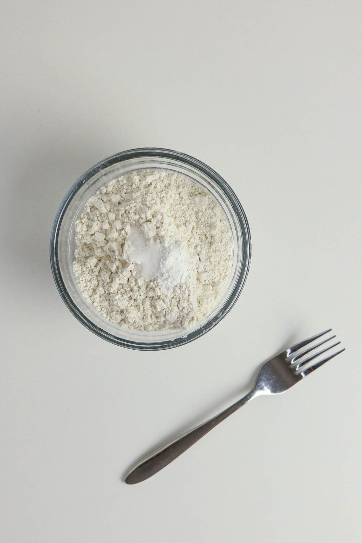 Dry ingredients being mixed in a glass bowl.