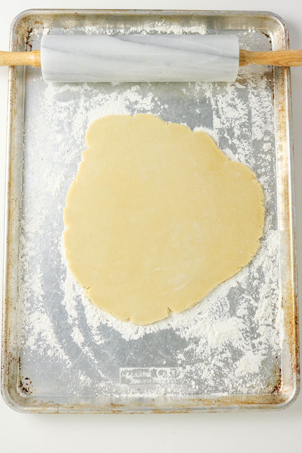 Dough being rolled out on a baking sheet.