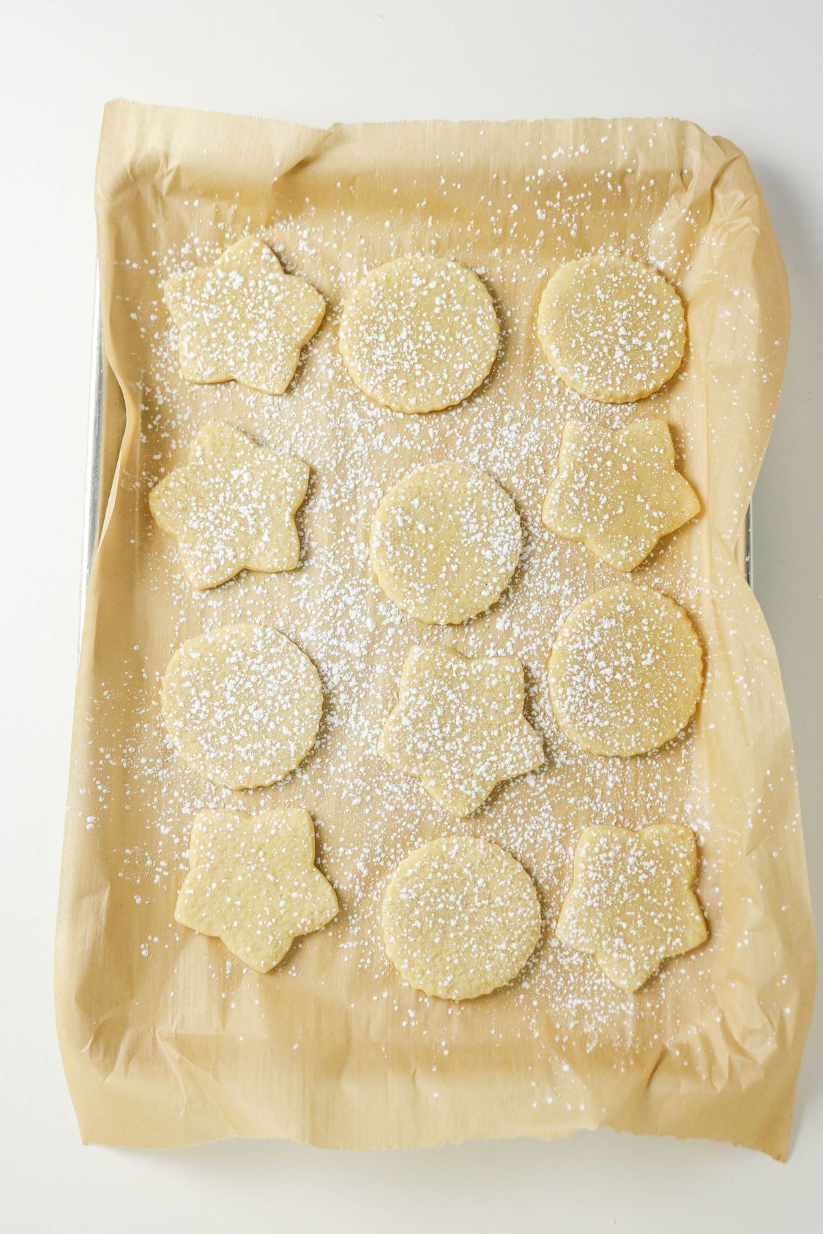 Cutout dough shapes on a parchment lined baking sheet.