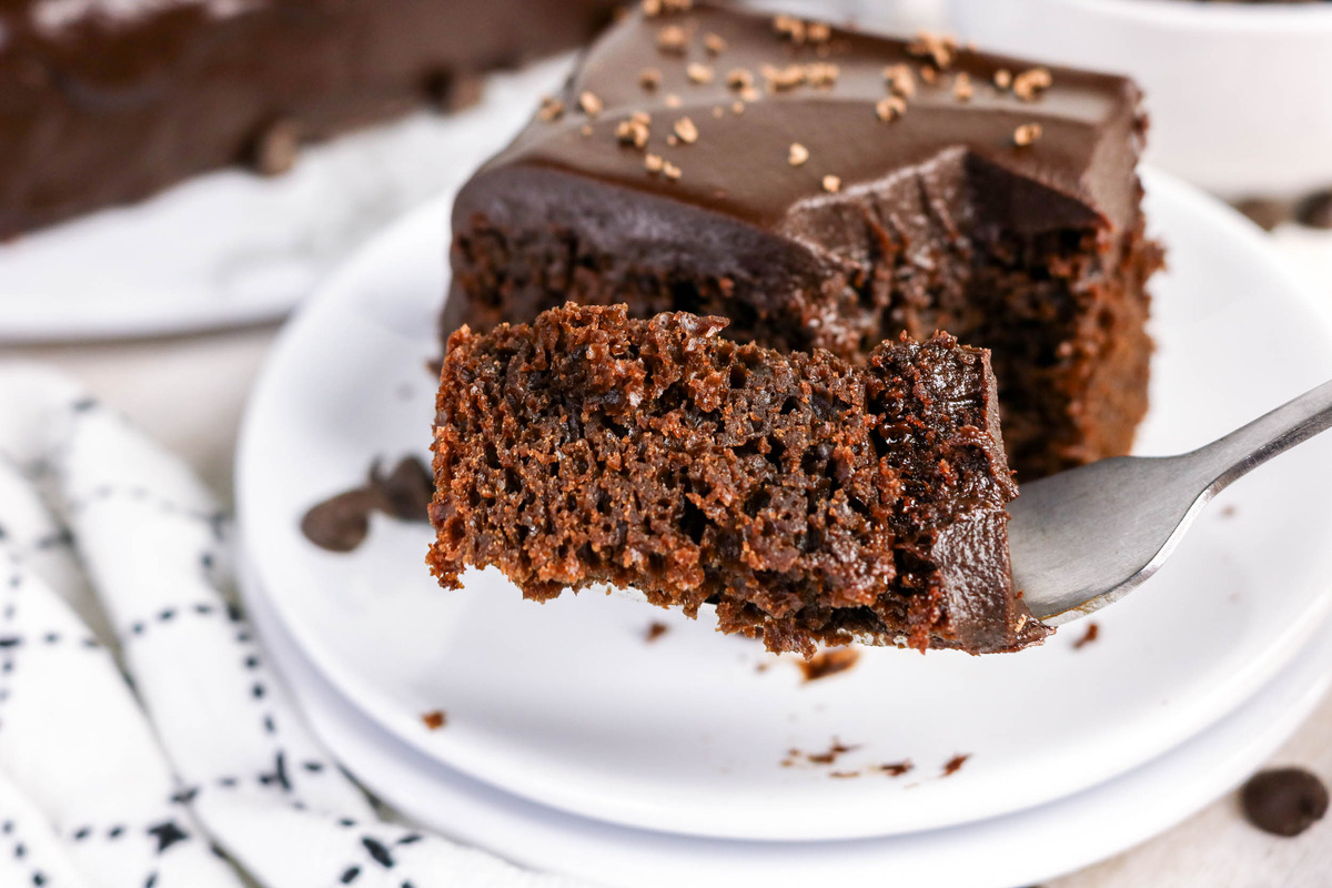 Chocolate cake with chocolate frosting with a forkful taken out of it.