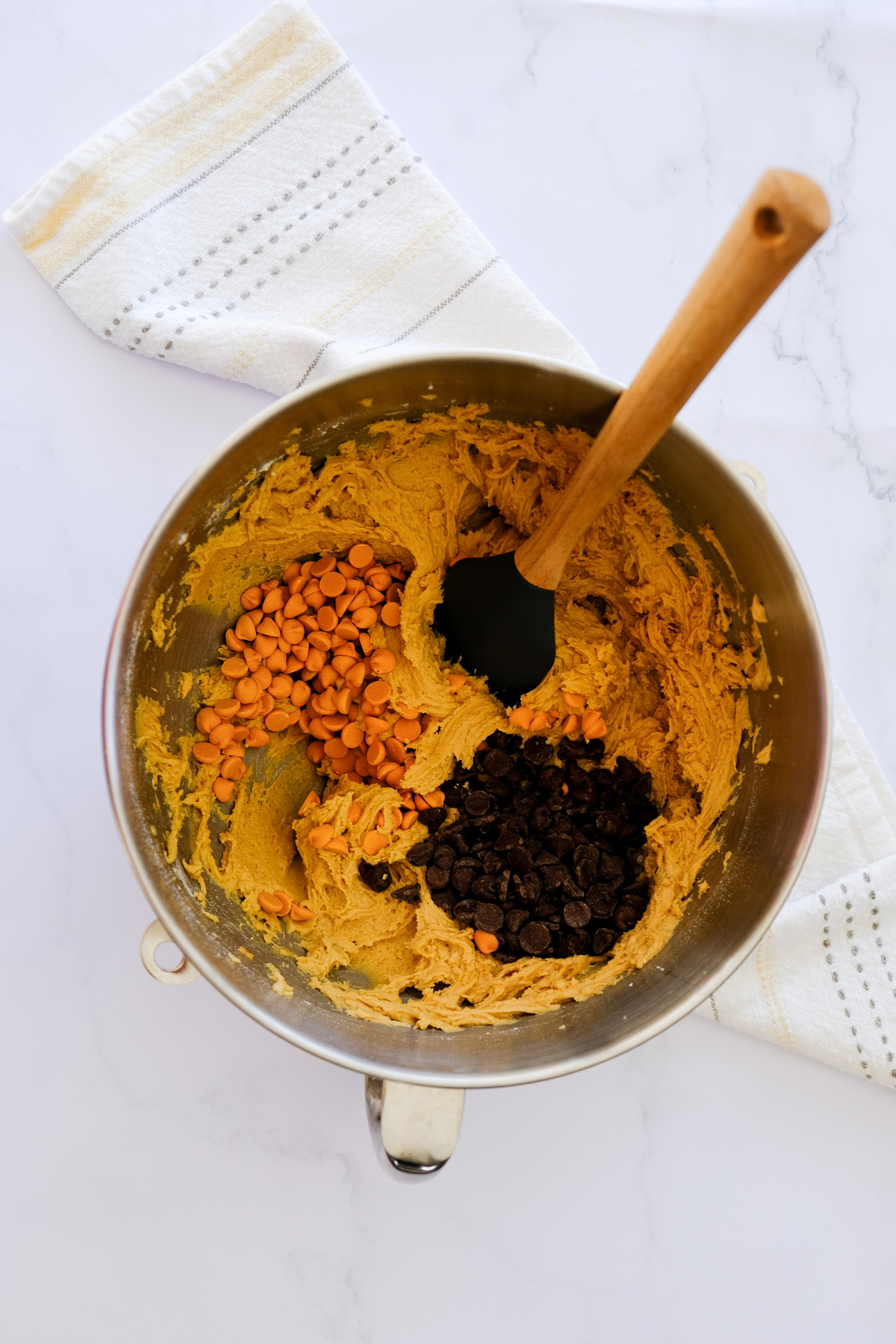 Folding in chocolate chips and peanut butter chips into cookie dough.