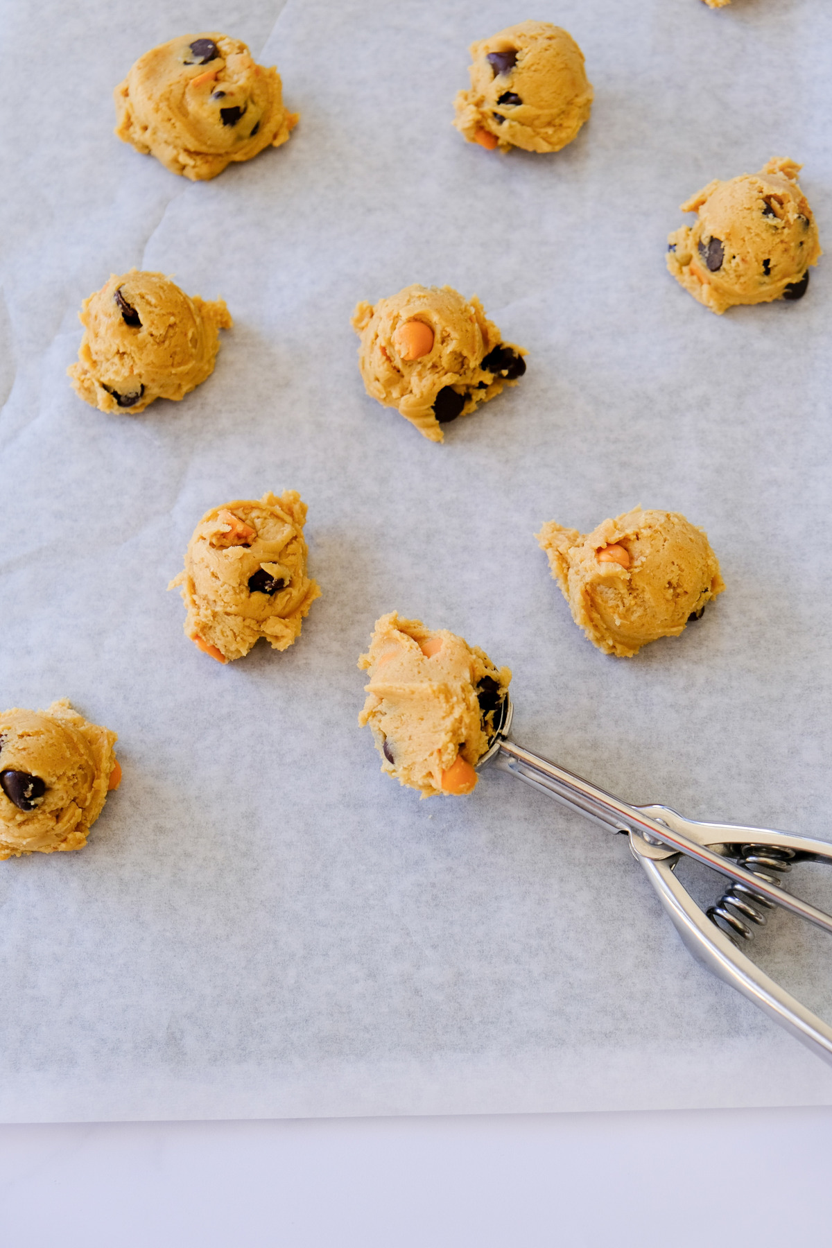 Cookie dough scooped onto parchment paper before baking.