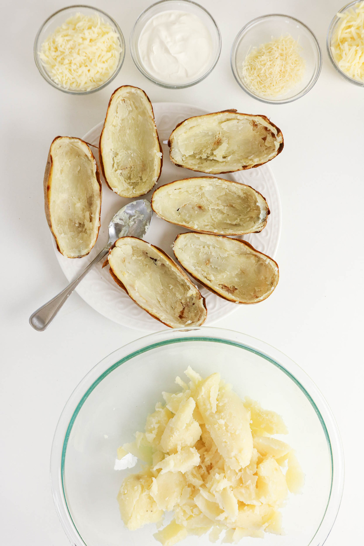 The flesh of a cooked baked potato scooped out and placed in a mixing bowl.
