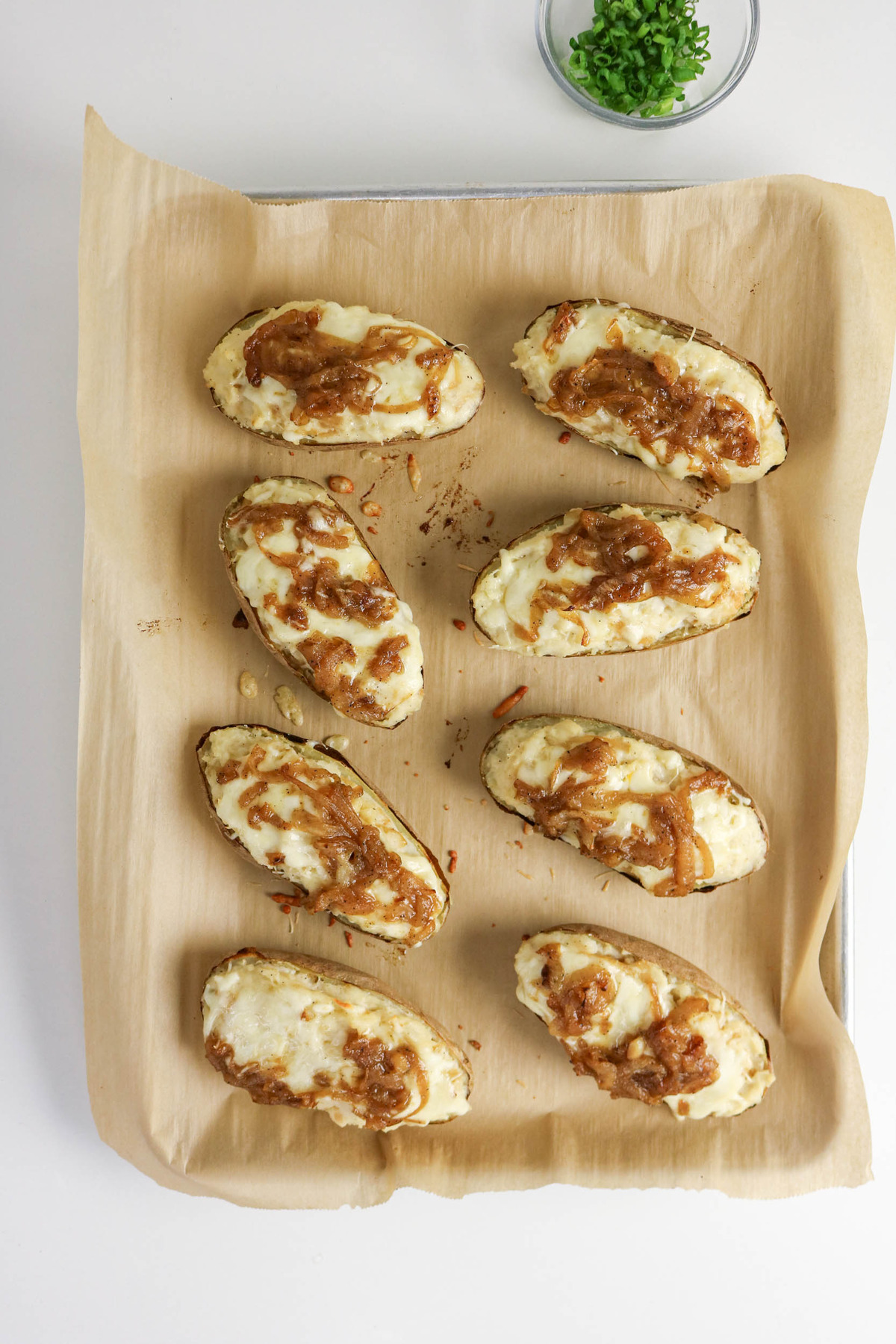 Slice potatoes stuffed with potato filling and topped with cheese before baking.