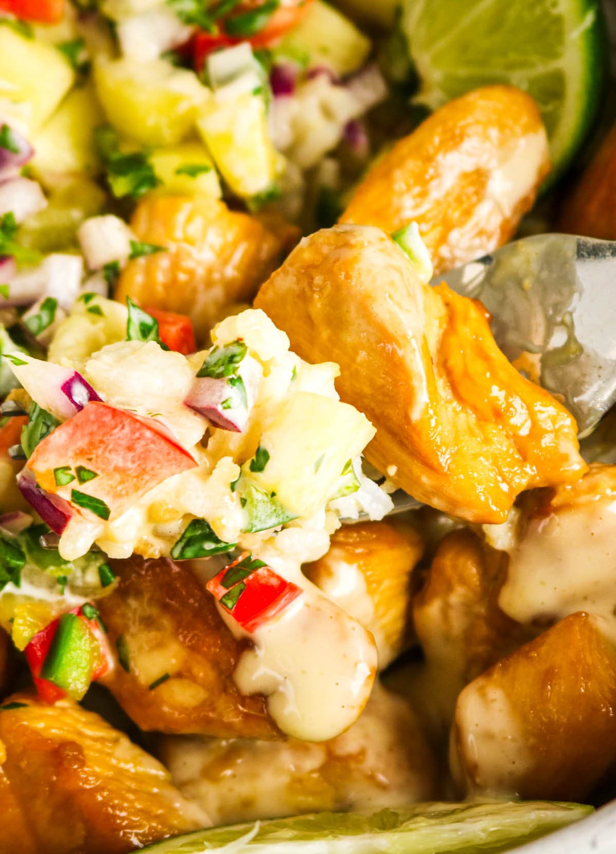Close view of a forkful of chicken with pineapple salsa.