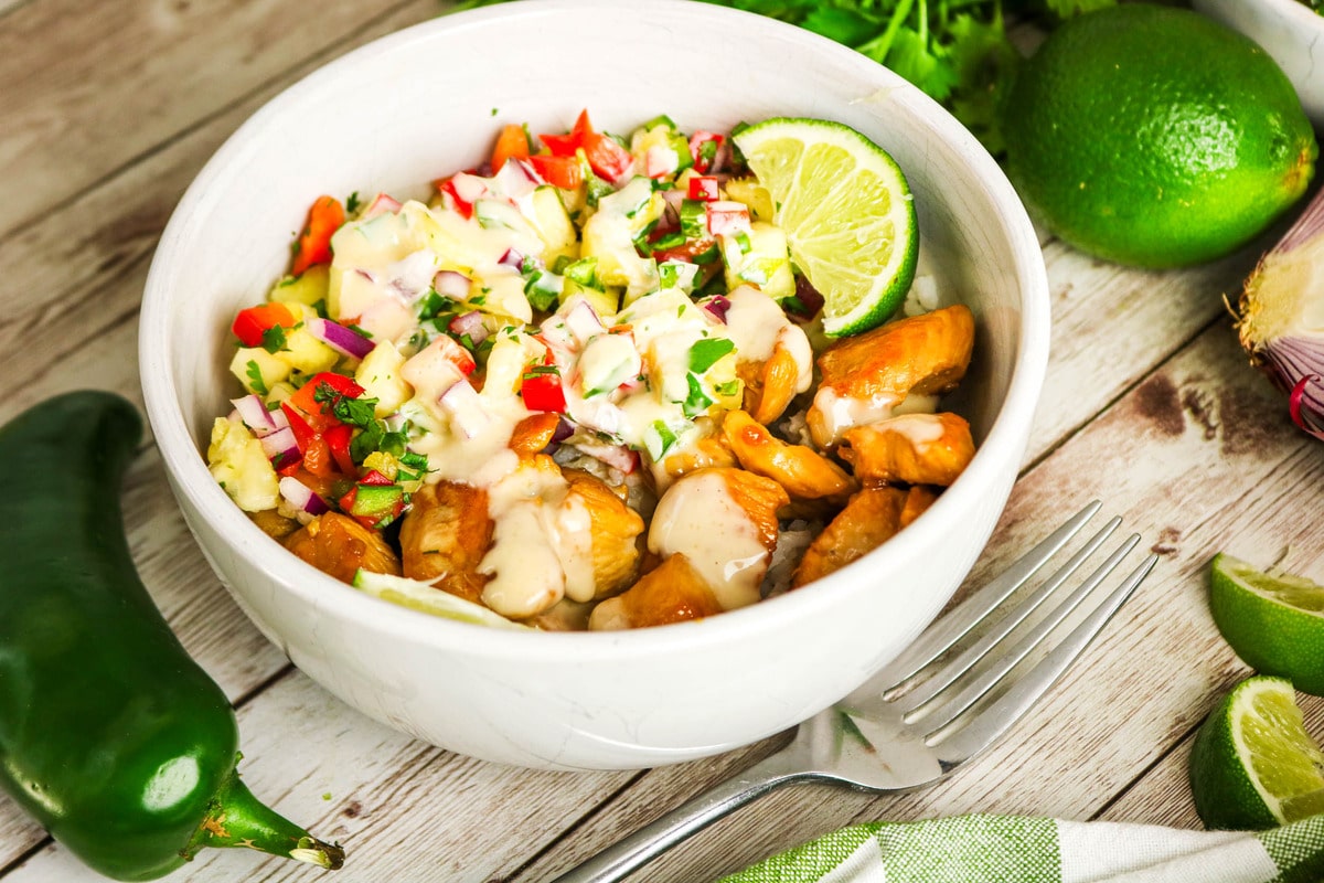 Landscape view of pineapple chicken bowl with lime on the side.