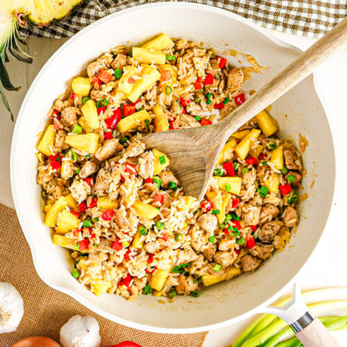 Pineapple and chicken fried rice in a large skillet with a spoon ready to enjoy.