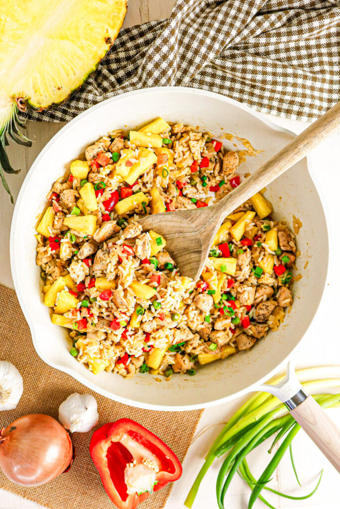 Pineapple and chicken fried rice in a large skillet with a spoon ready to enjoy.