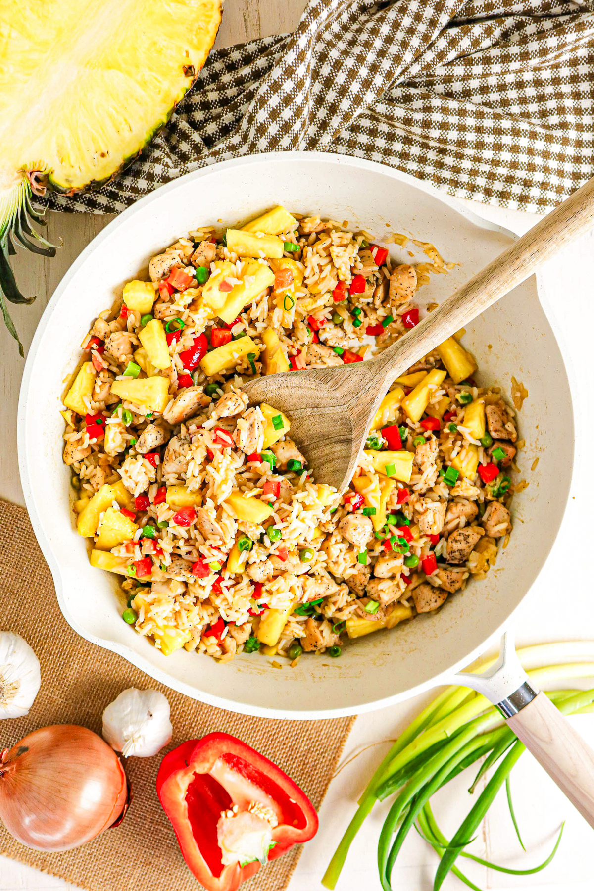 Pineapple and chicken fried rice in a large skillet with a spoon ready to enjoy.