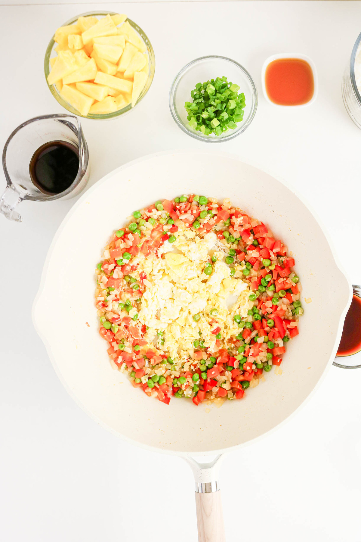 Scrambled eggs in the middle of a skillet surrounded by vegetables.