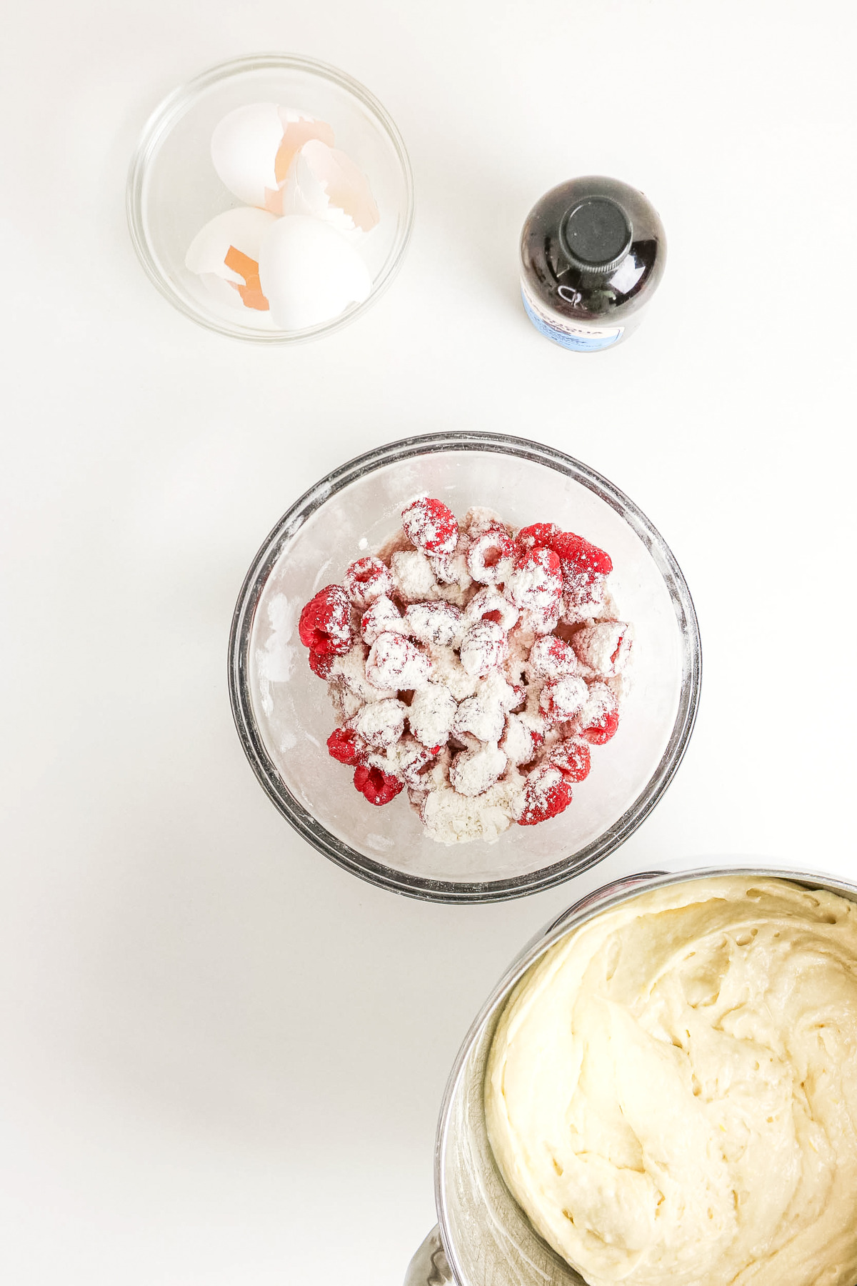 Fresh raspberries tossed with flour in a clear mixing bowl.