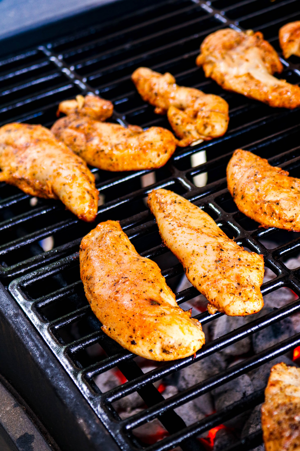 Chicken tenderloins on a grill grate being cooked.