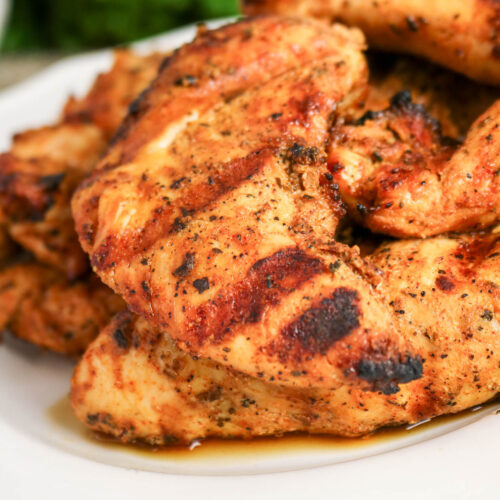 A white dinner plate topped with grilled chicken tenderloins.