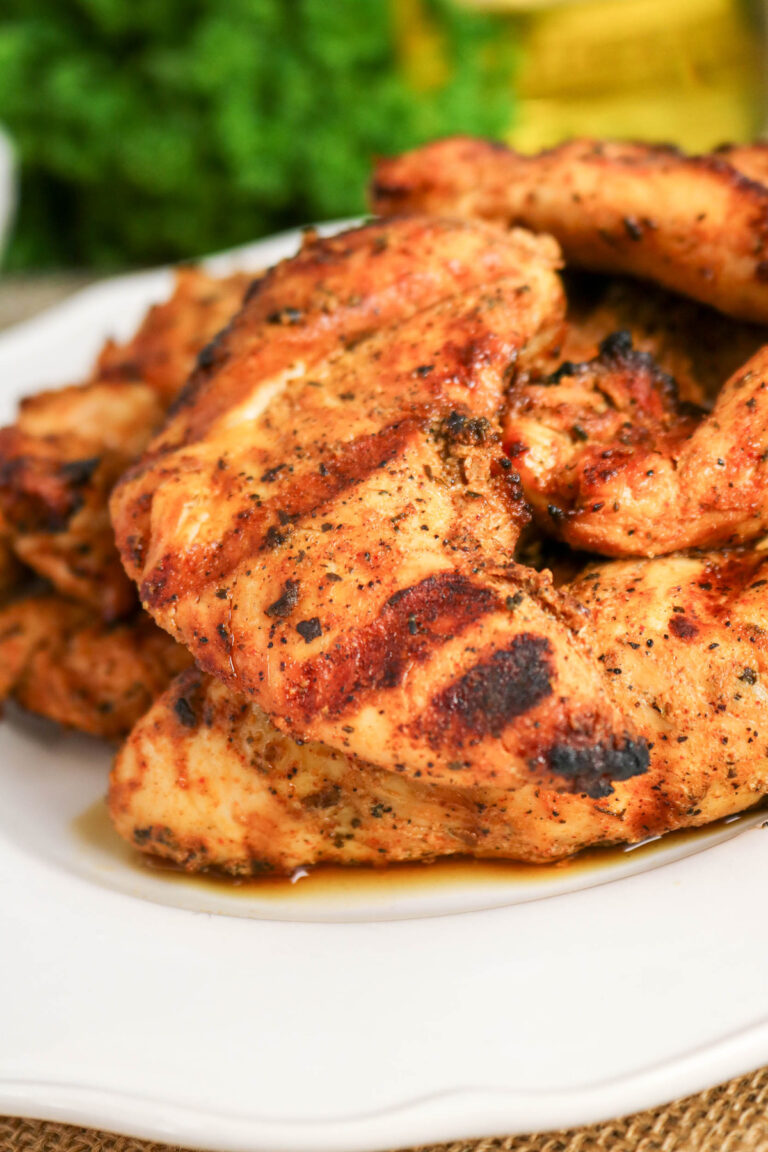 A white dinner plate topped with grilled chicken tenderloins.