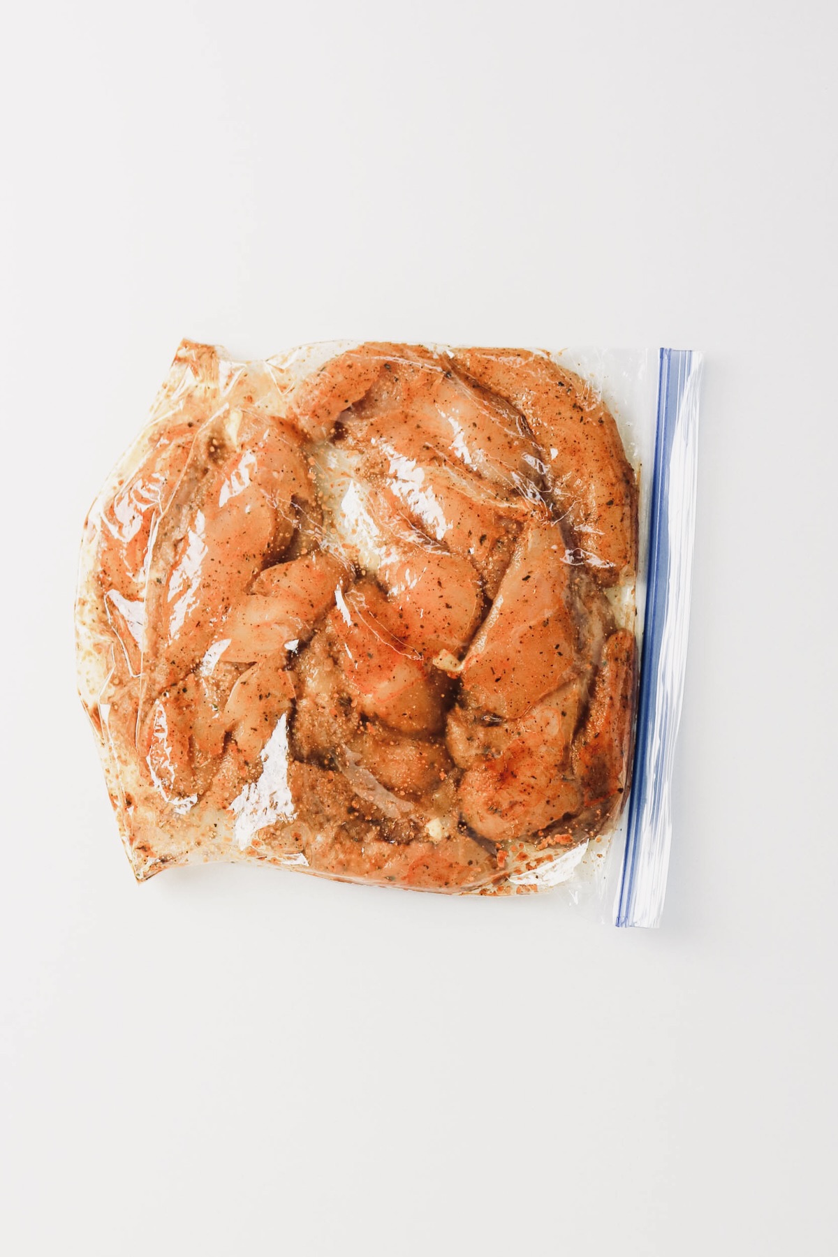 Chicken tenders marinating in a plastic bag.